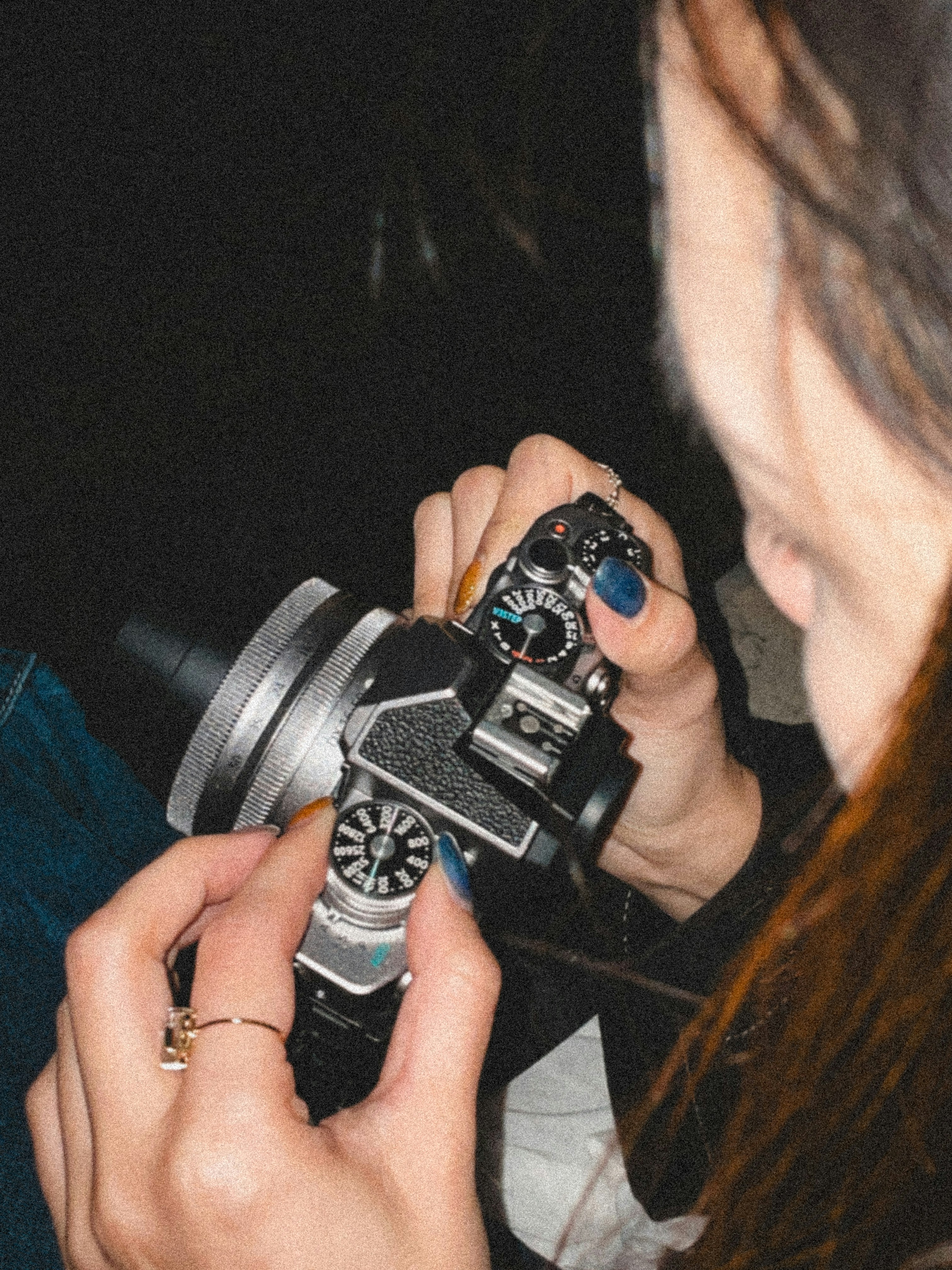 A person is holding a camera, adjusting settings.