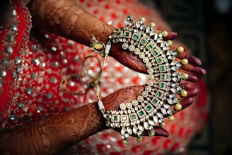 Jeweled necklace is held with henna-decorated hands.