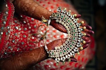 Jeweled necklace is held with henna-decorated hands.