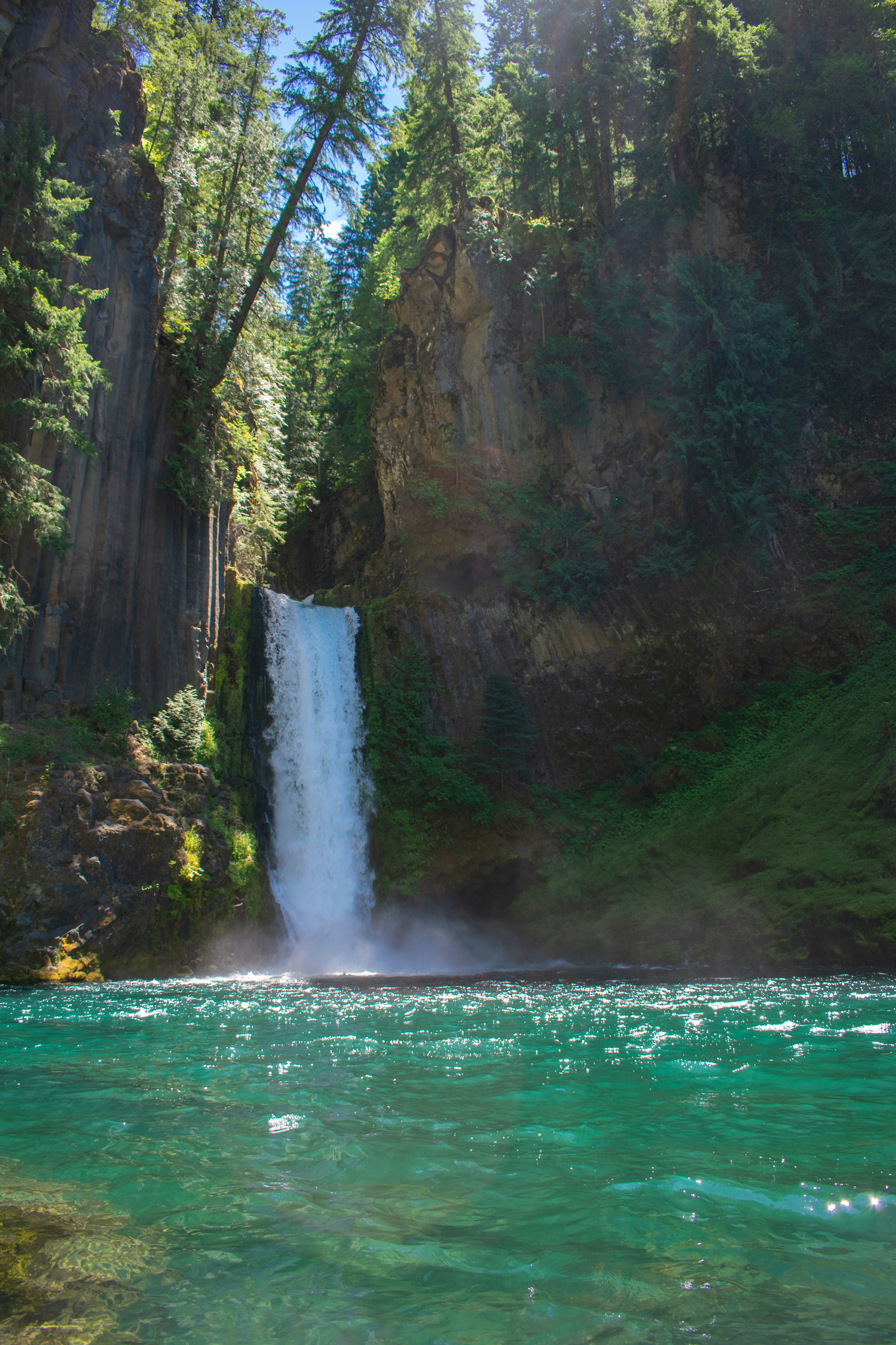 Una maestosa cascata sfocia in un lago turchese.