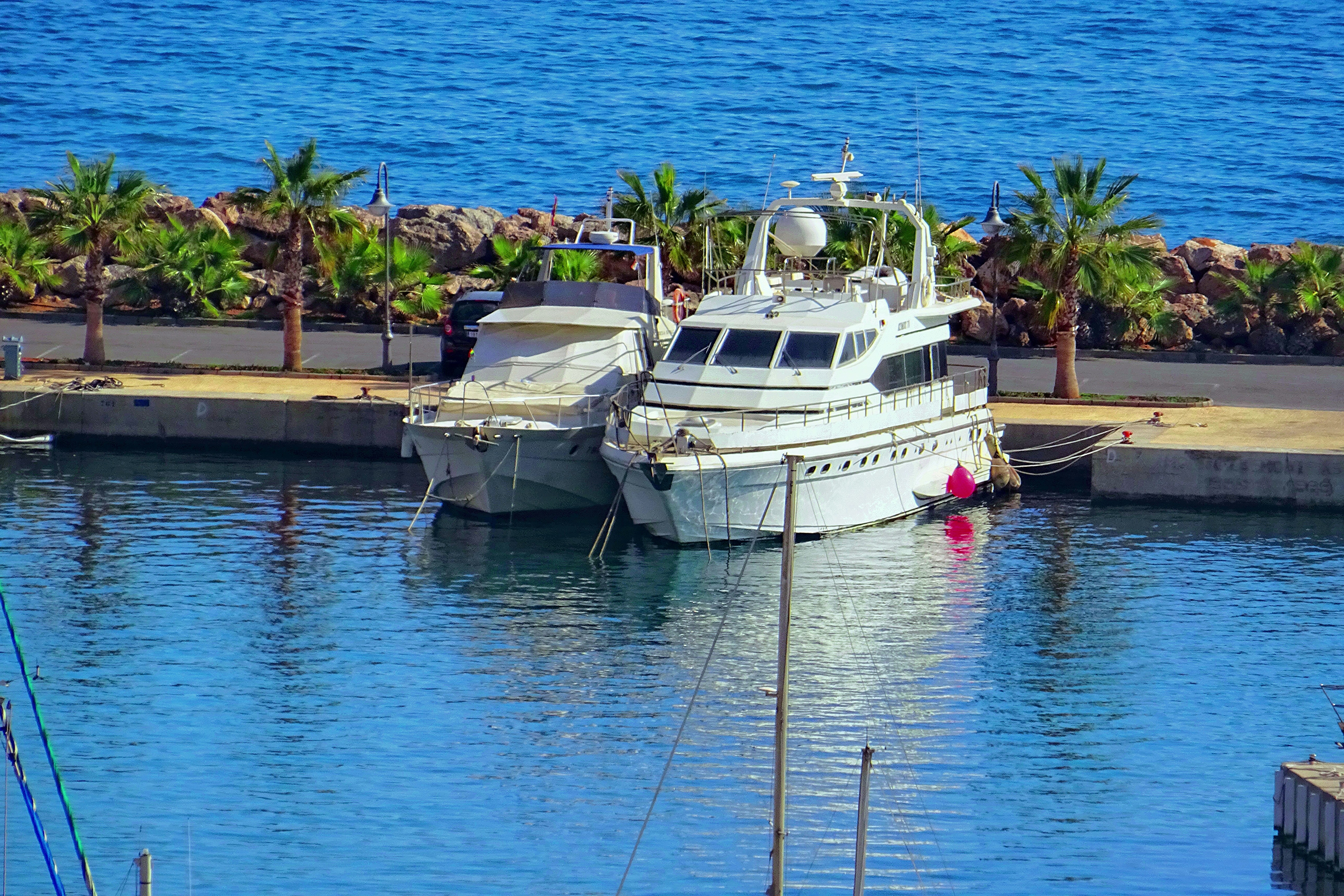 Two boats docked in a harbor on a sunny day.