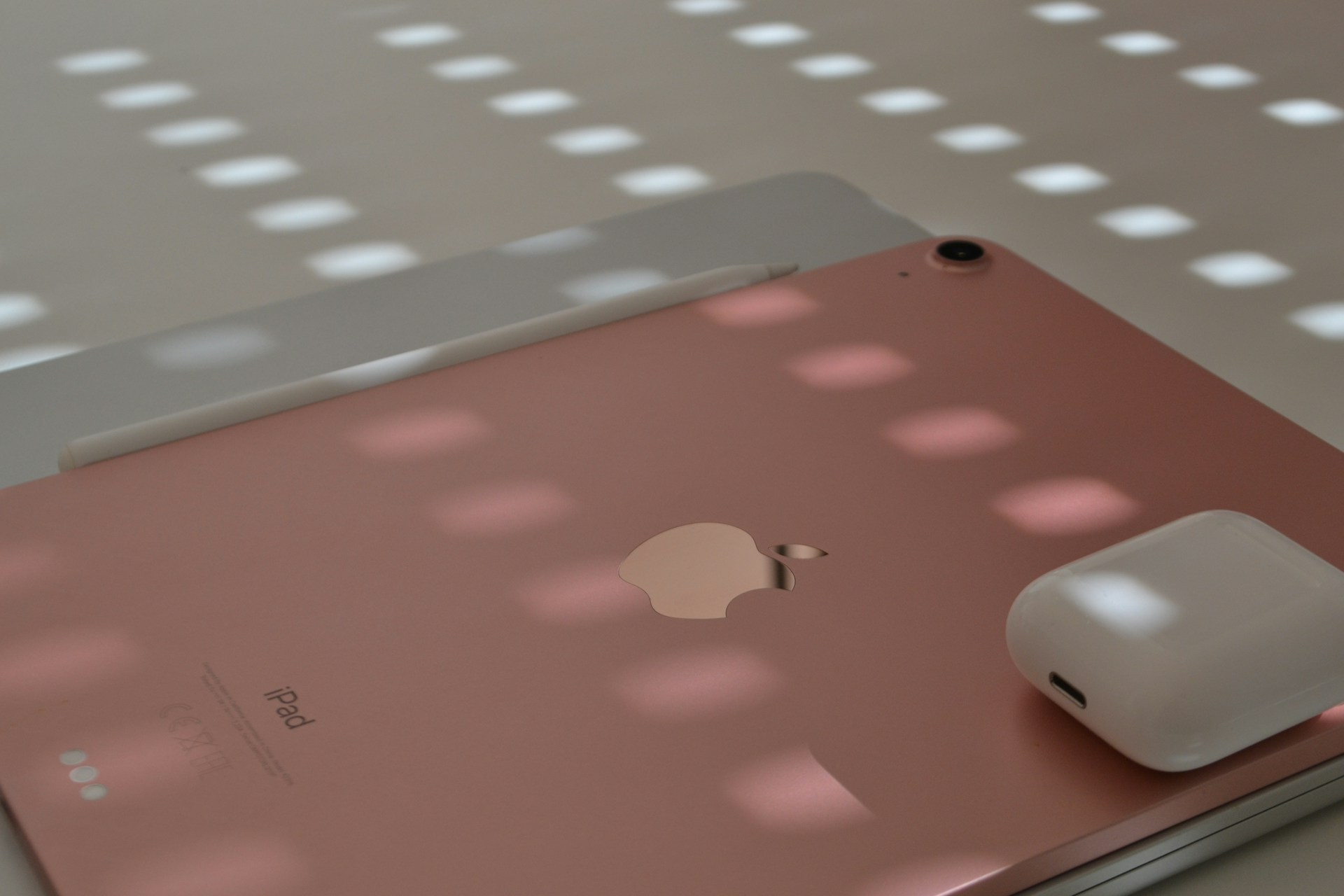 An iPad and airpods sit under sunlight.