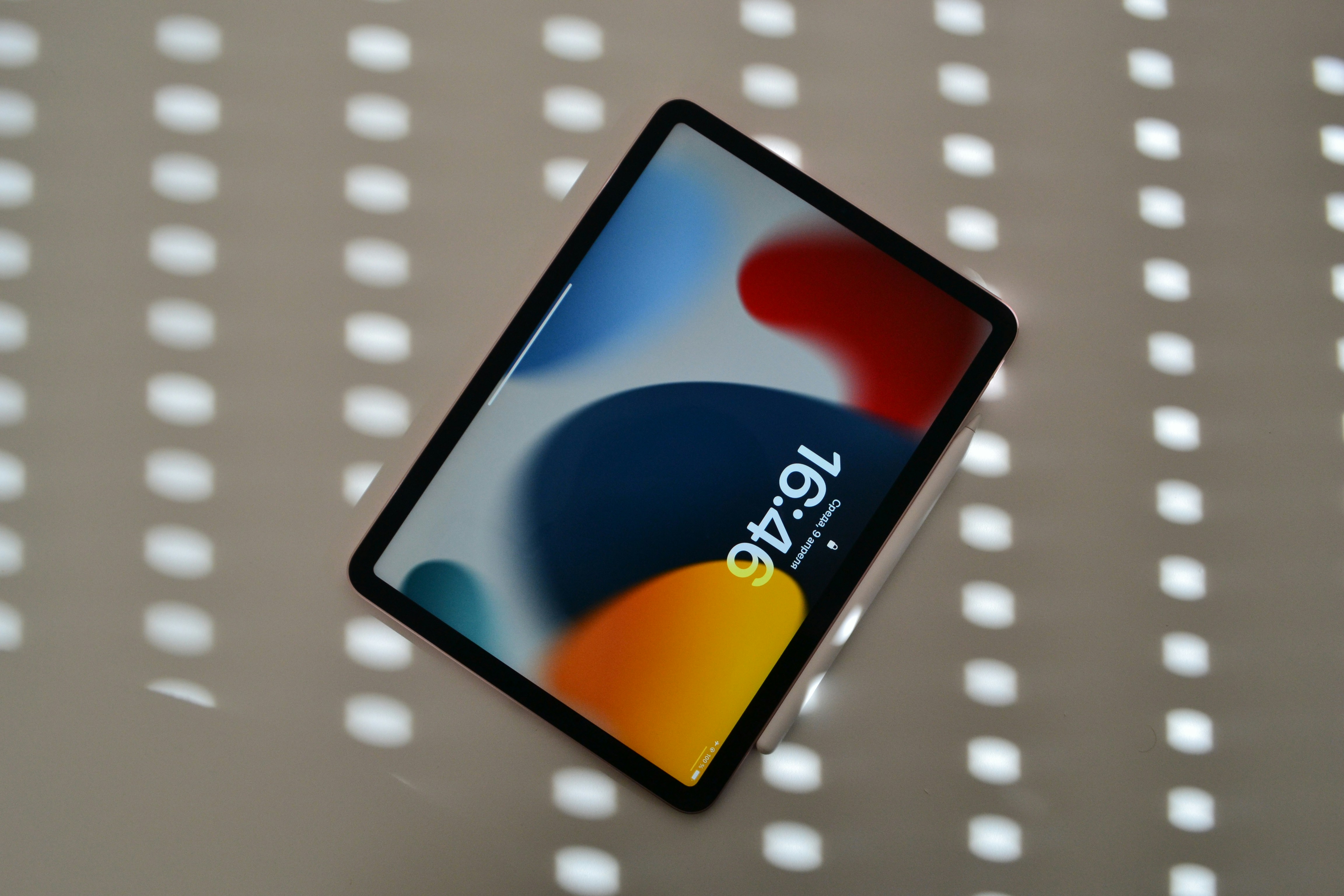 An iPad lies on a reflective surface.