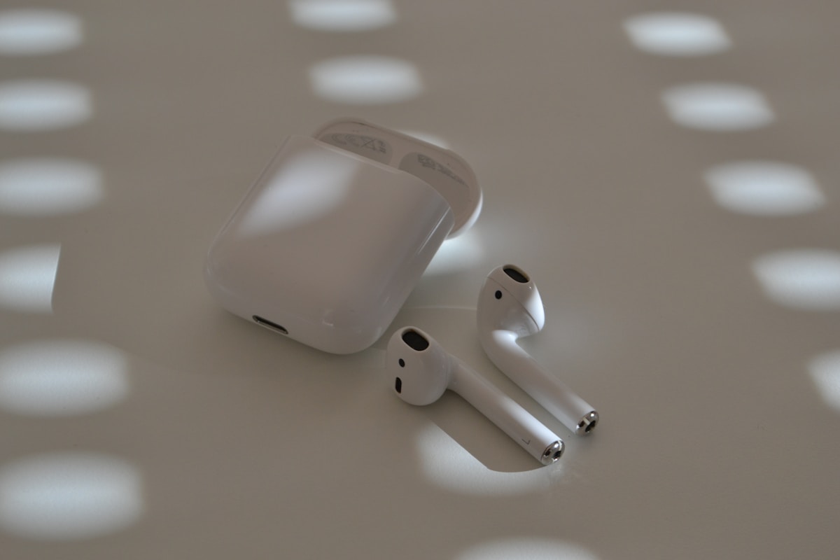 Airpods and their case sit on a white surface.