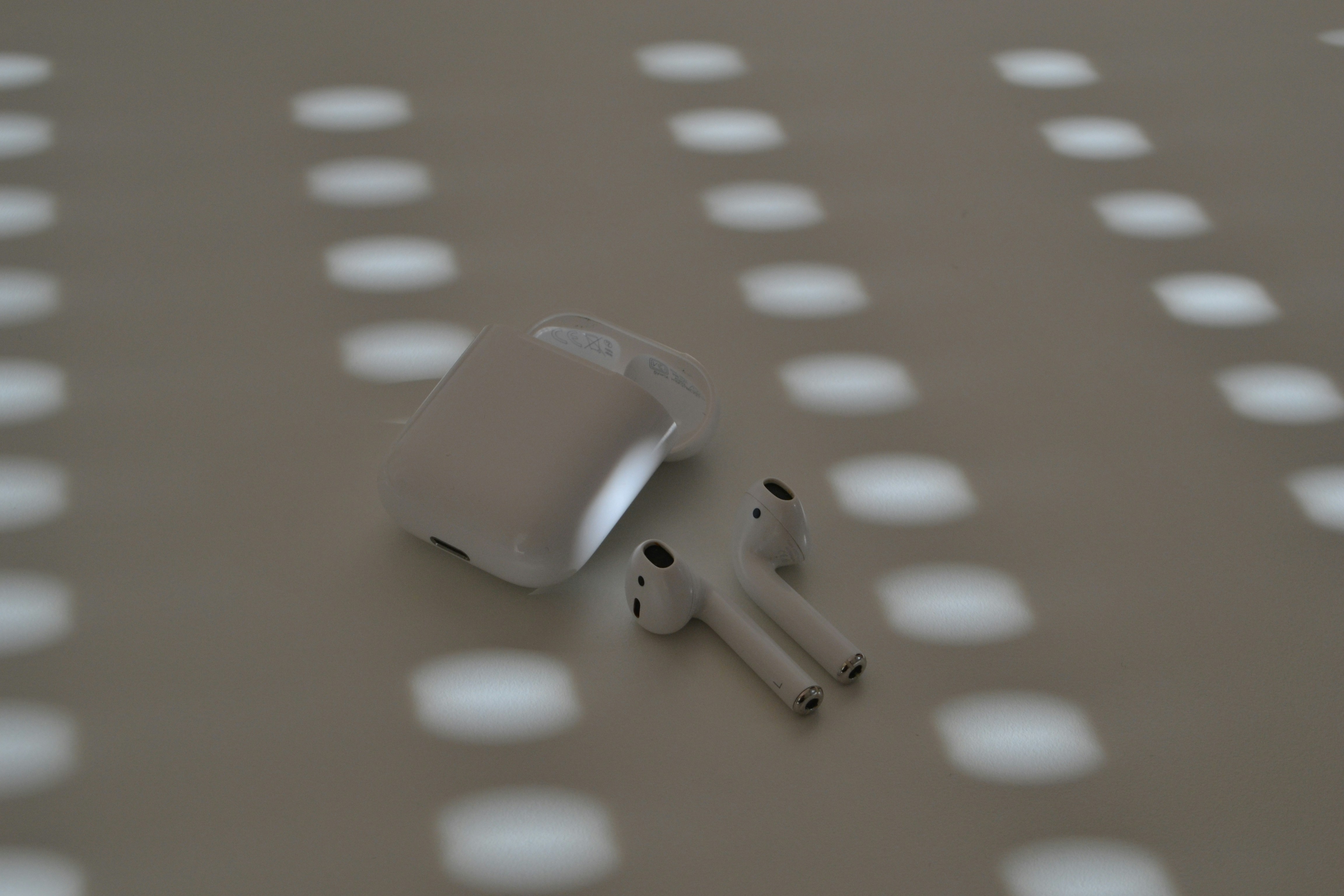 Airpods and charging case on a patterned surface.