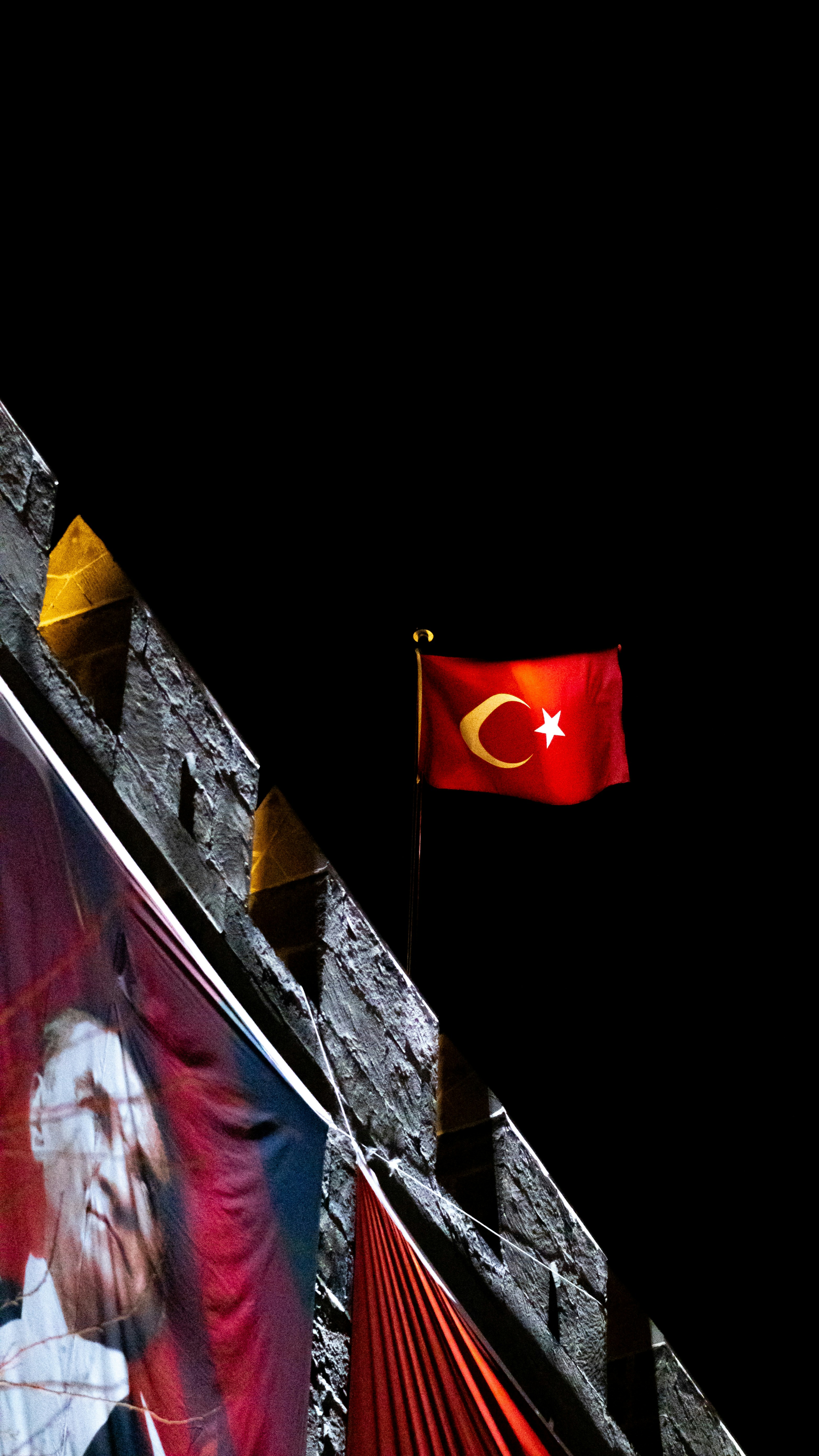 The turkish flag waves on a dark night.