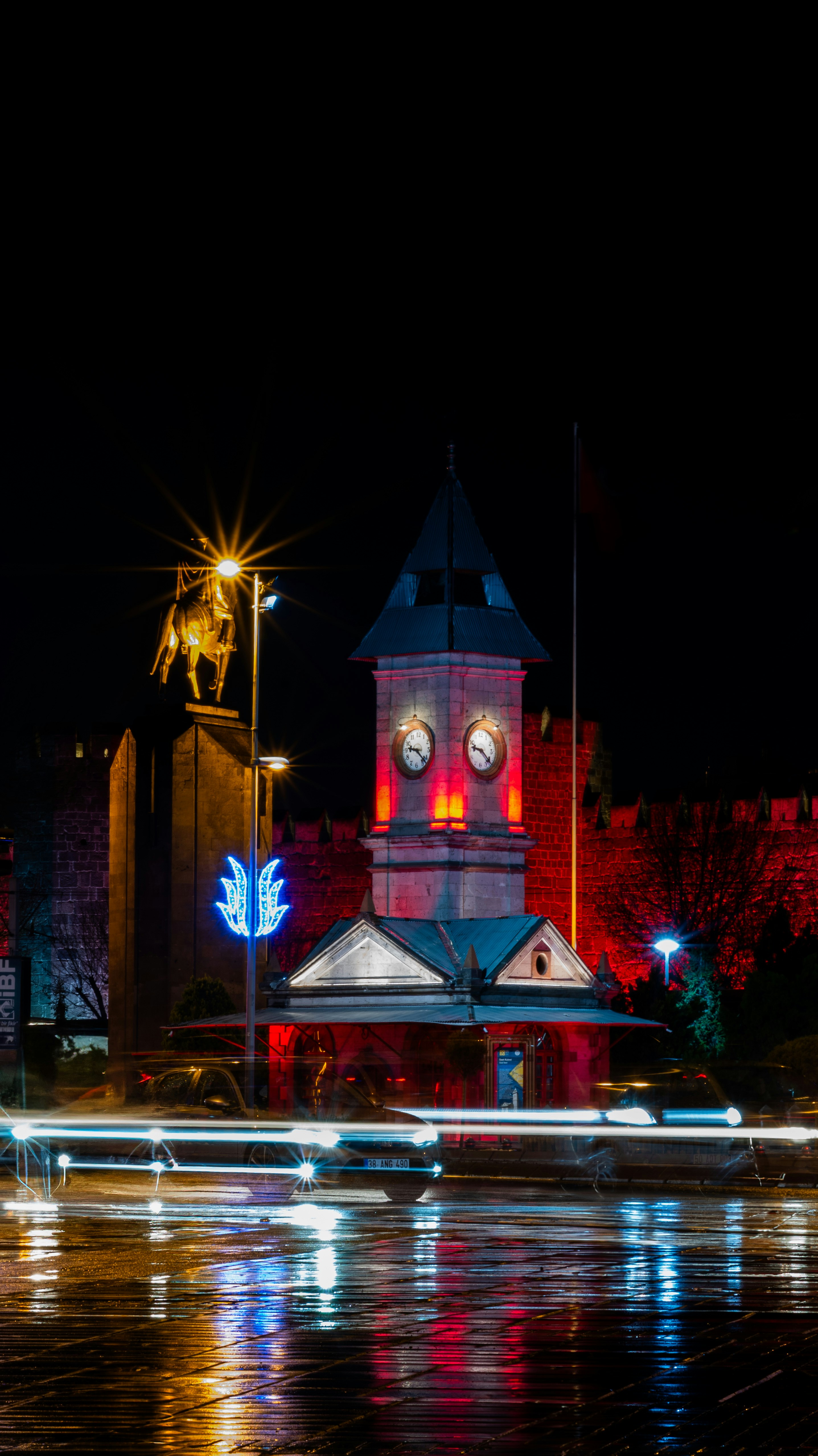 A clock tower and statue are illuminated at night
