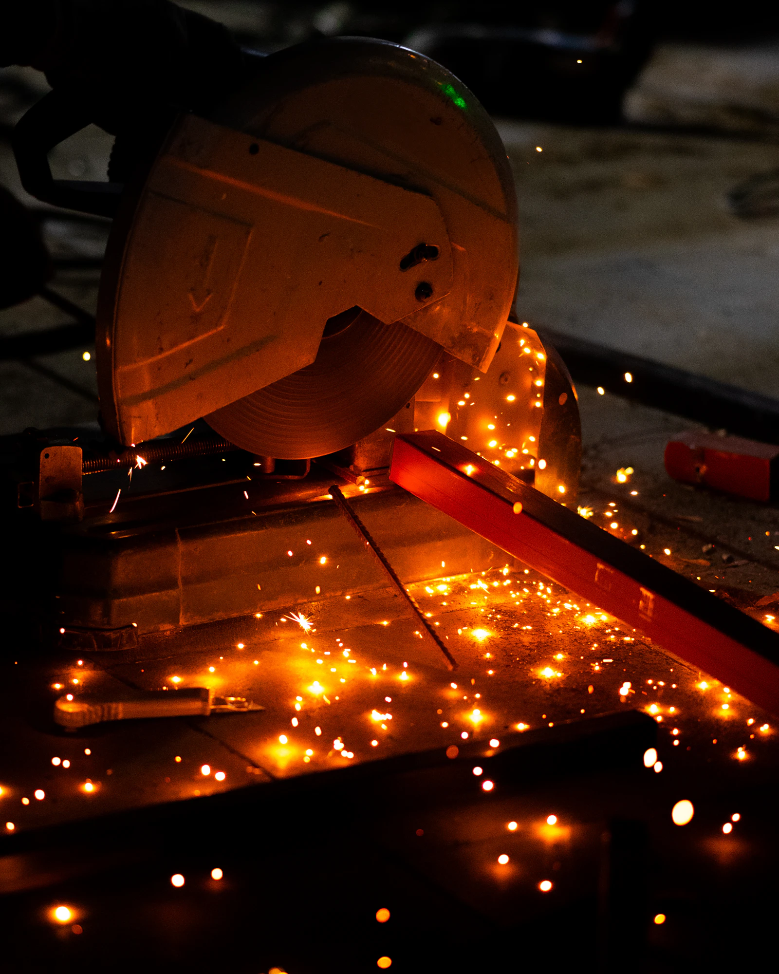 Metal saw cutting through steel with sparks flying in workshop
