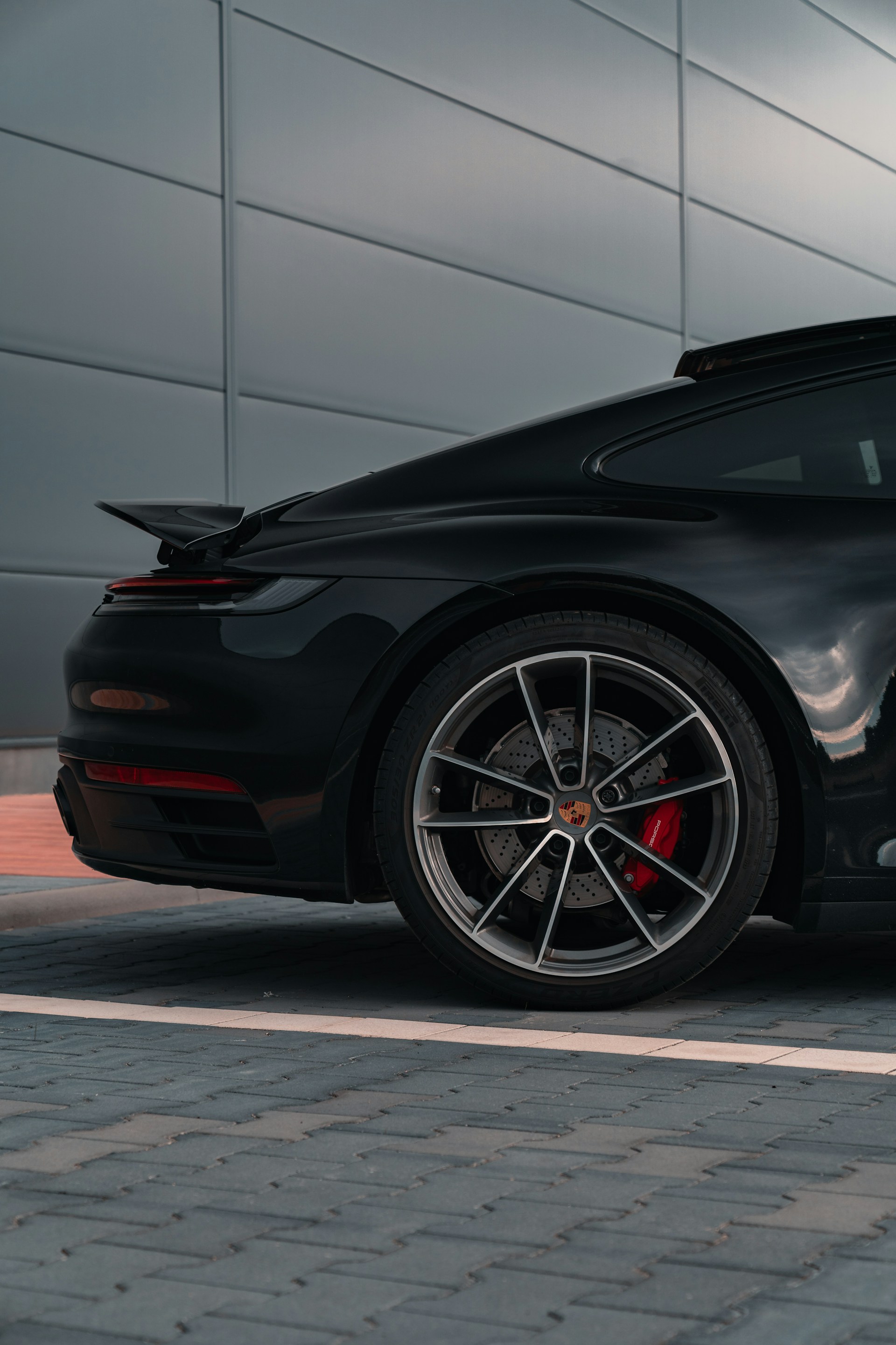 Here is a possible caption: a sleek black porsche showing off its wheel.