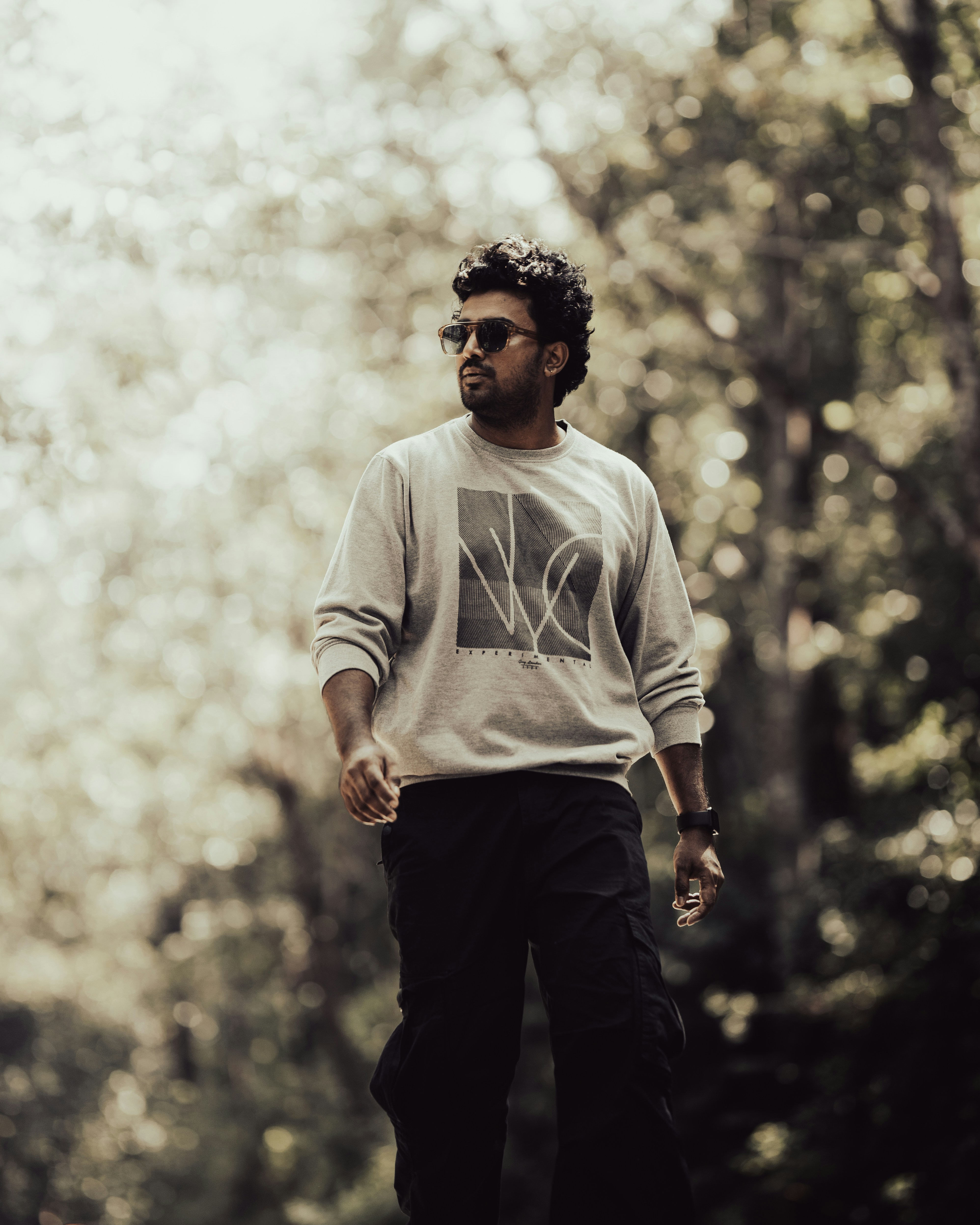 A man poses outdoors in stylish clothing.