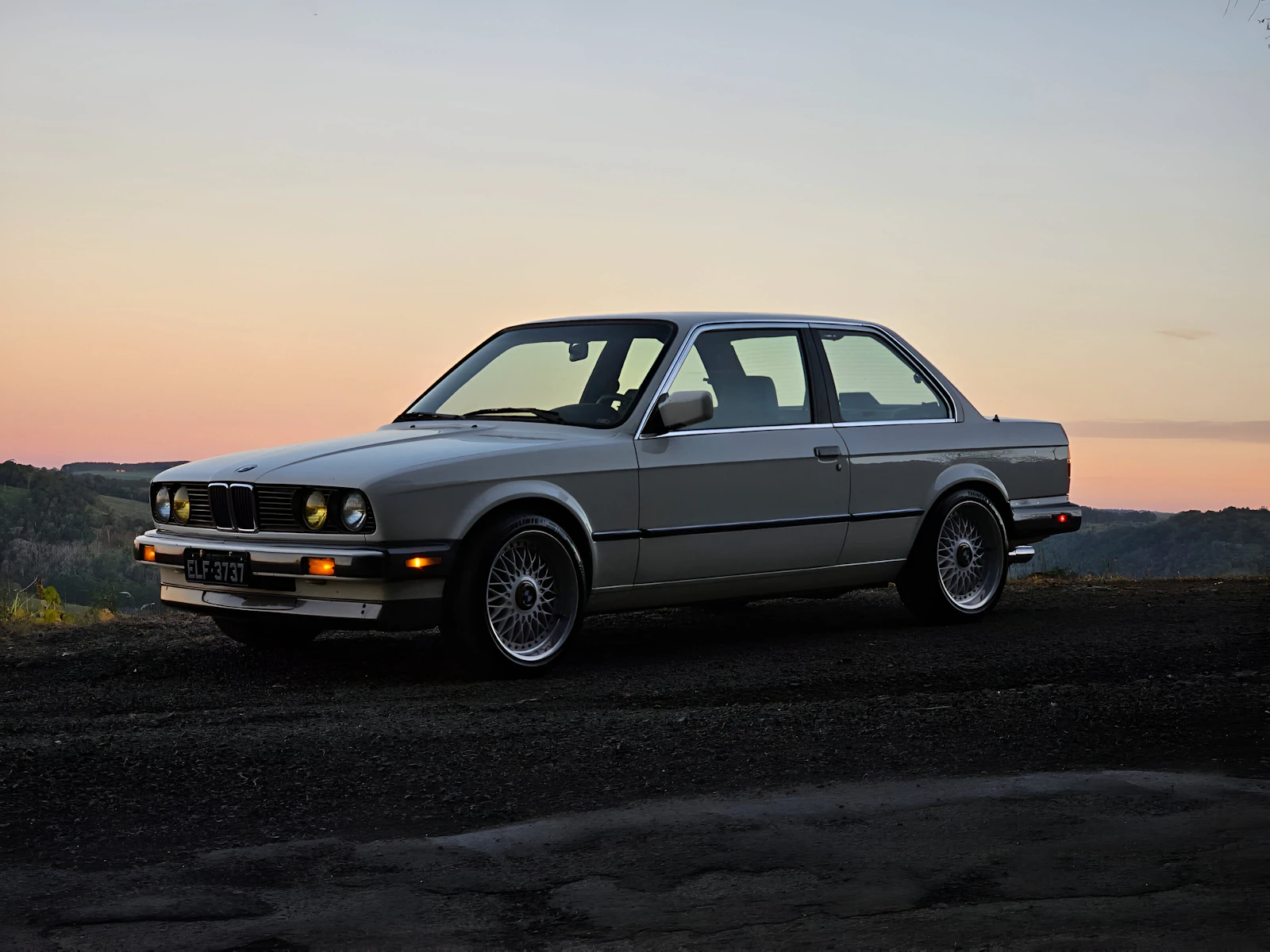 Classic 1990 BMW M3 parked at sunset