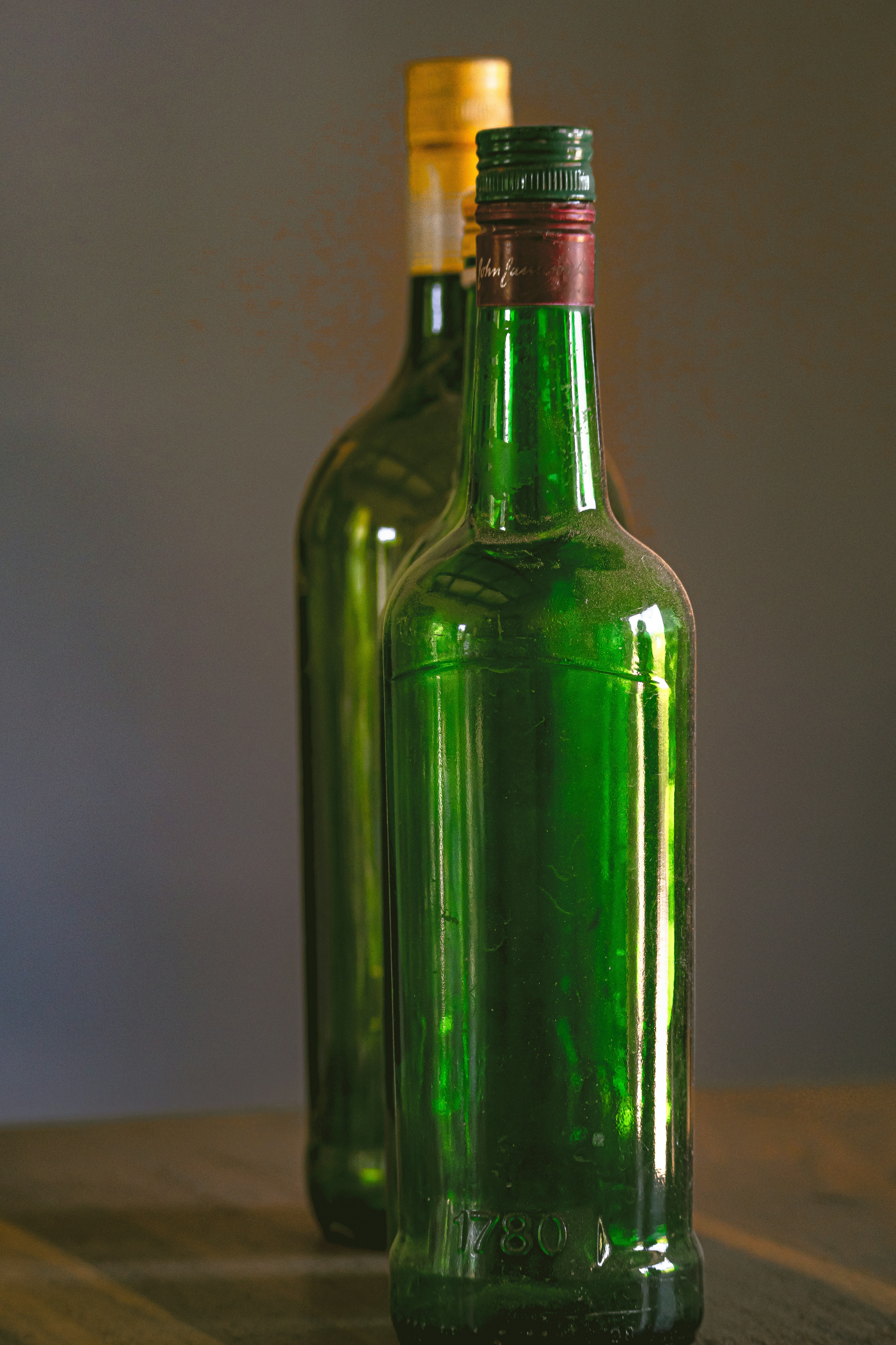 Two empty green bottles stand on a table.