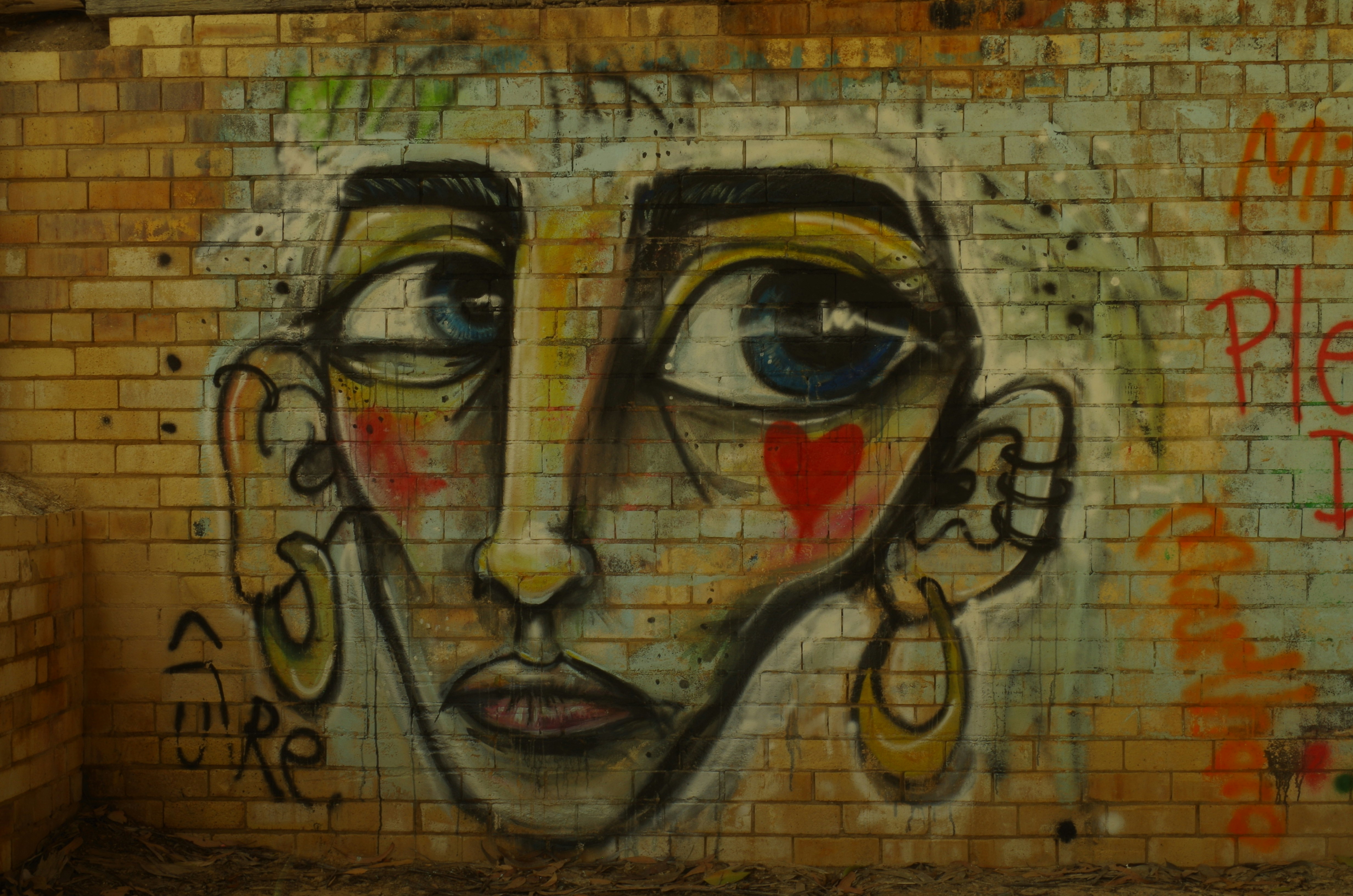 Graffiti-Kunst eines Gesichts auf einer Backsteinwand.