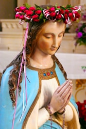 A statue of mary wears a beautiful flower crown.