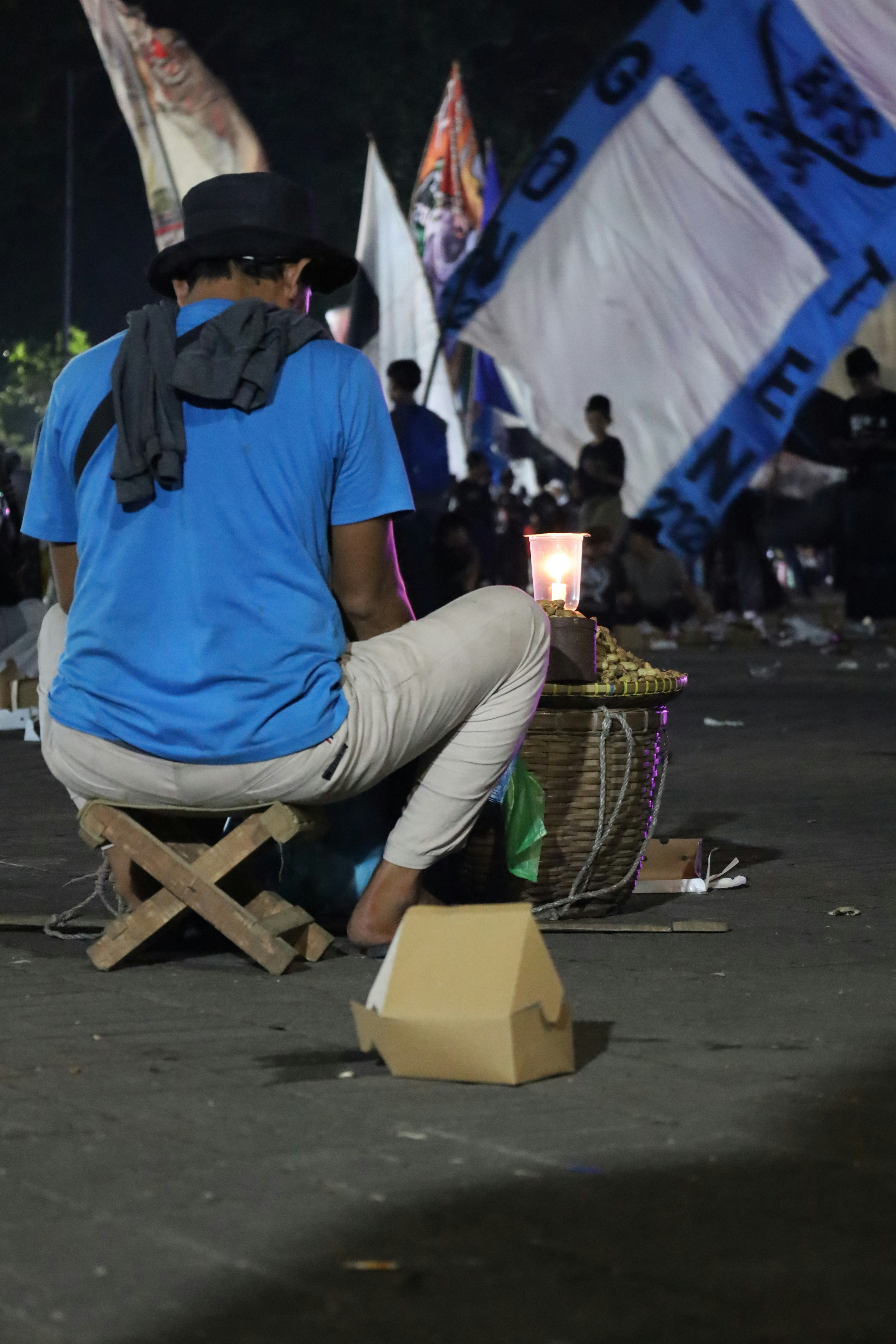 Pria duduk di malam hari, dikelilingi oleh bendera.
