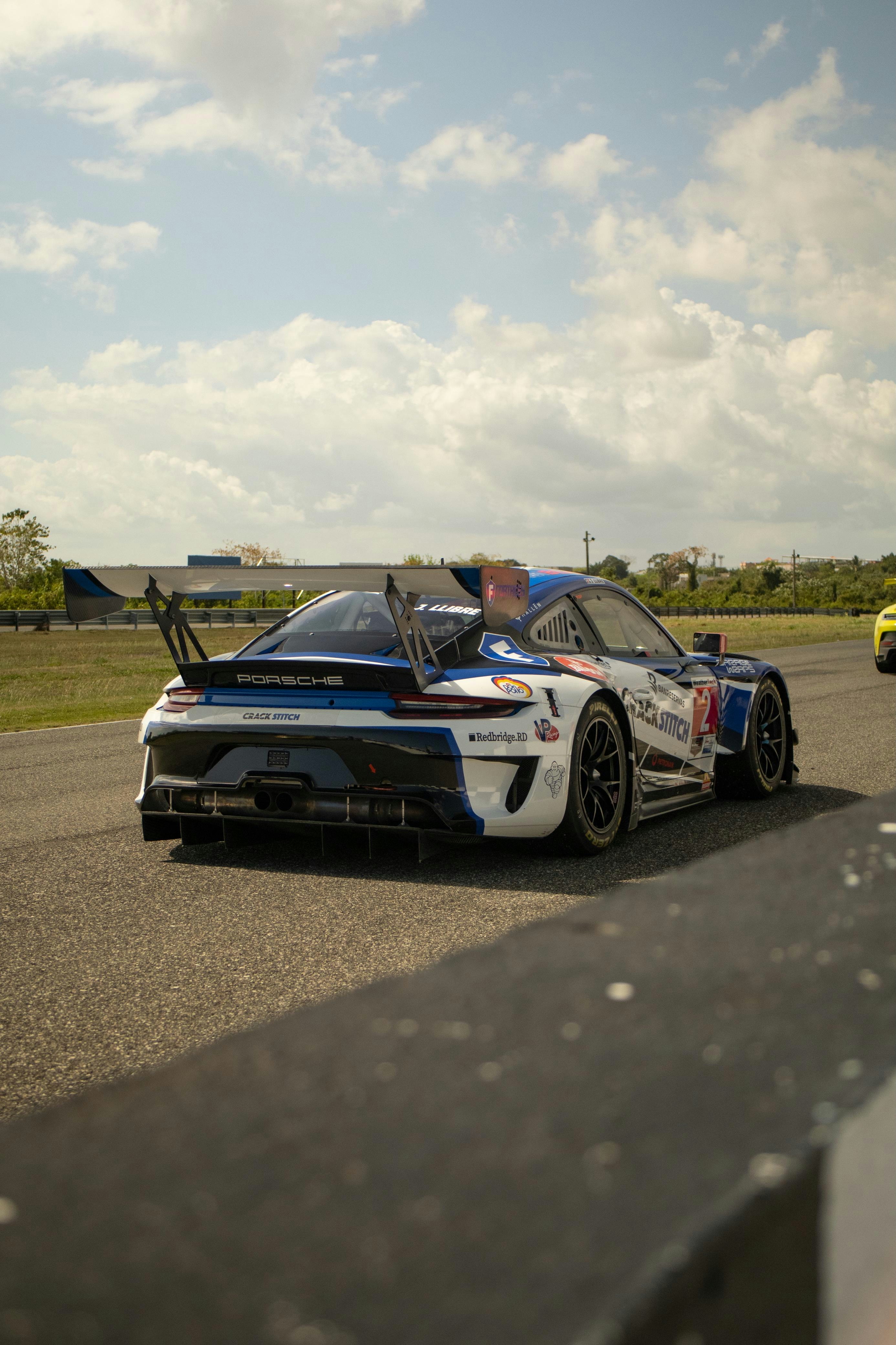 Um carro de corrida porsche branco e azul na pista.
