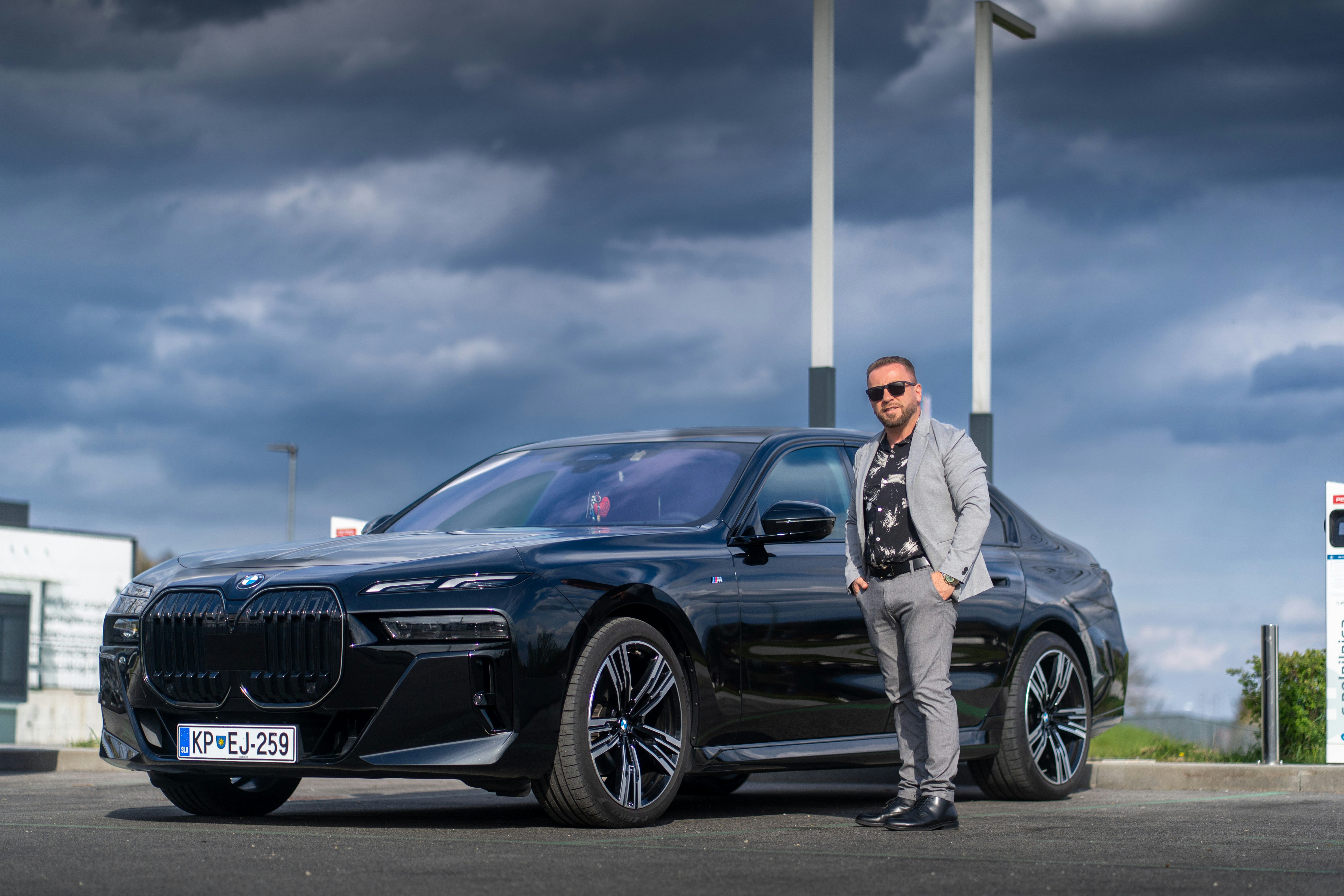 Man stands by a black BMW sedan.