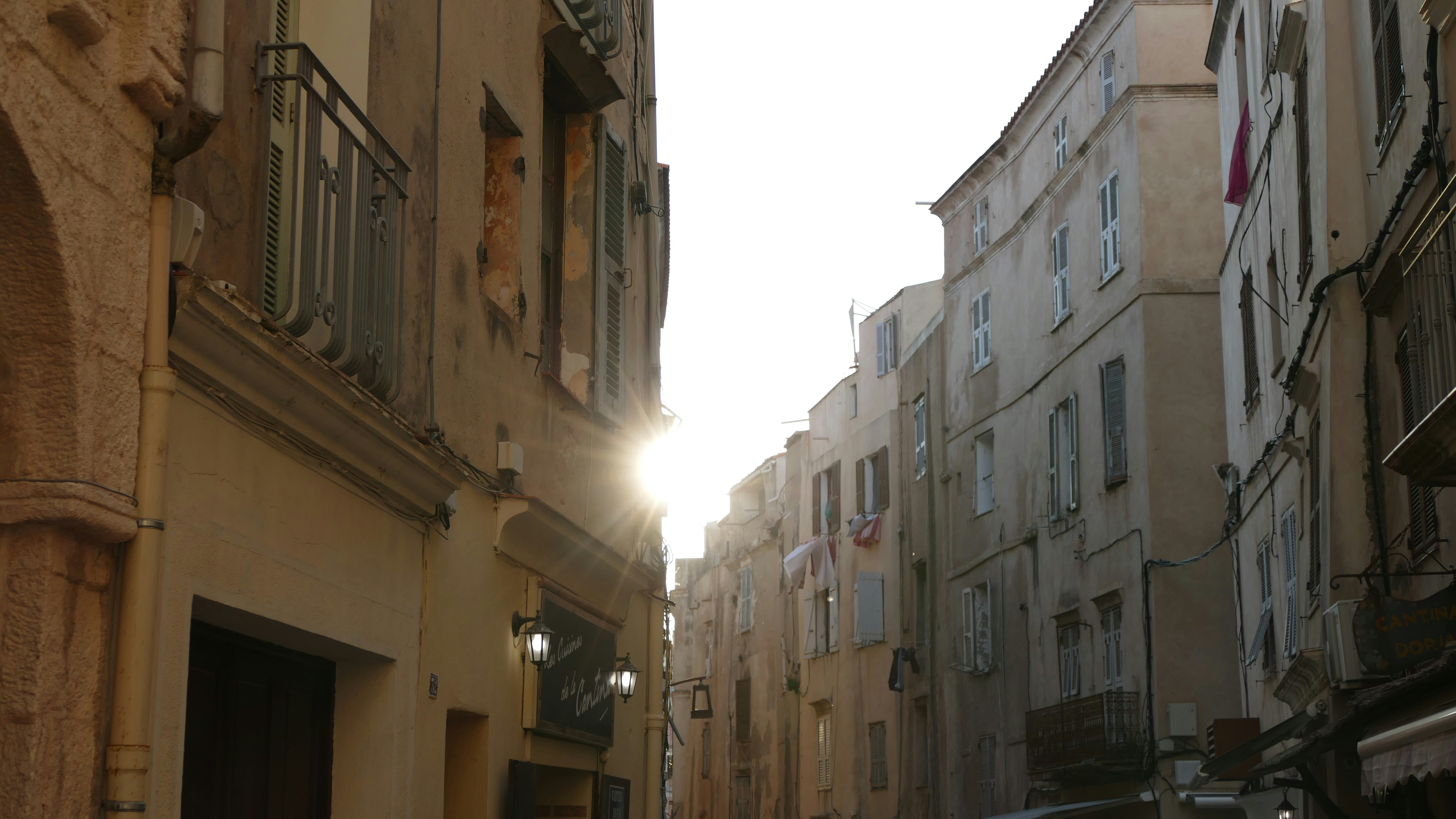 Buildings line a narrow european street at sunset.