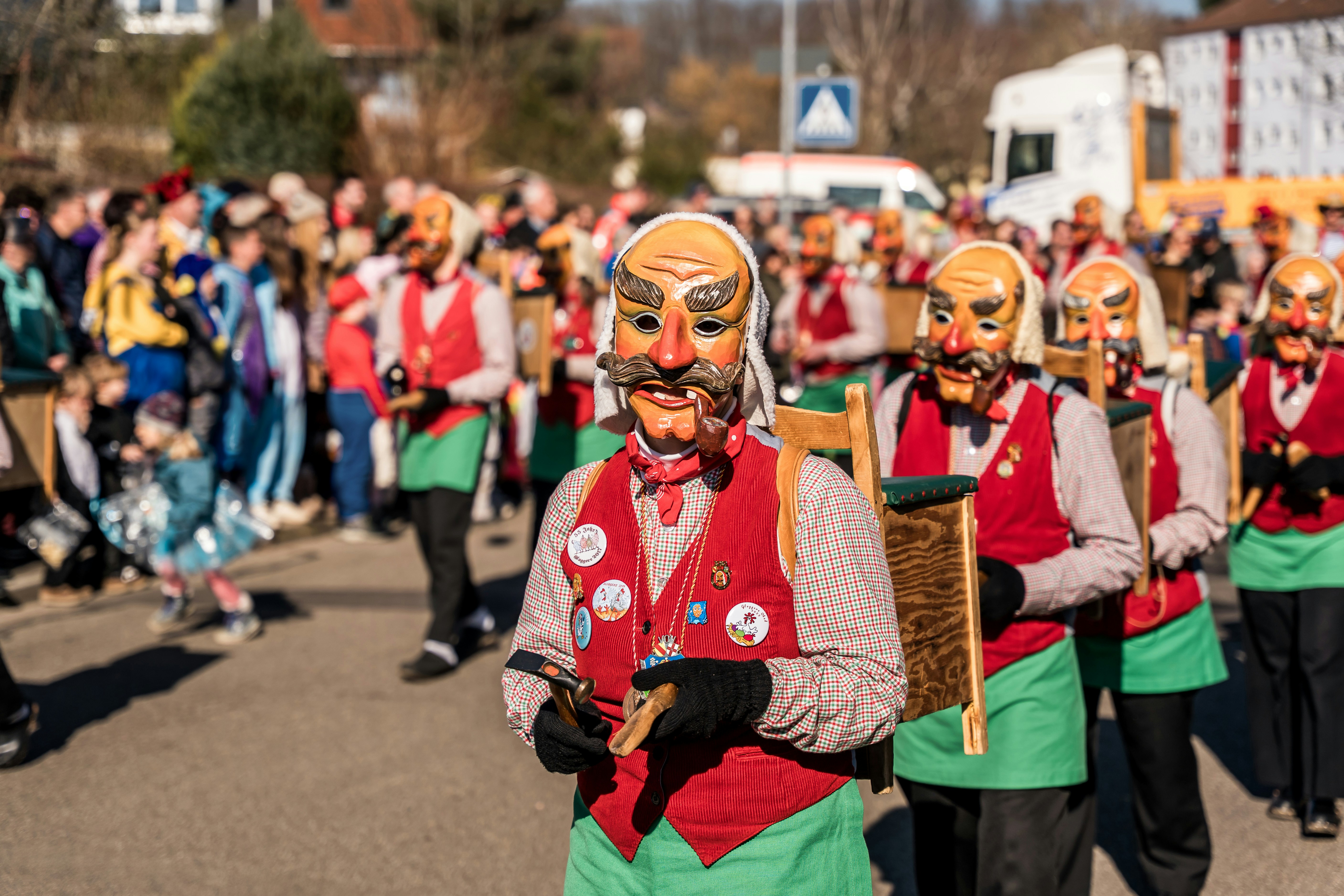 Persone in maschera marciano in una festosa parata di strada.