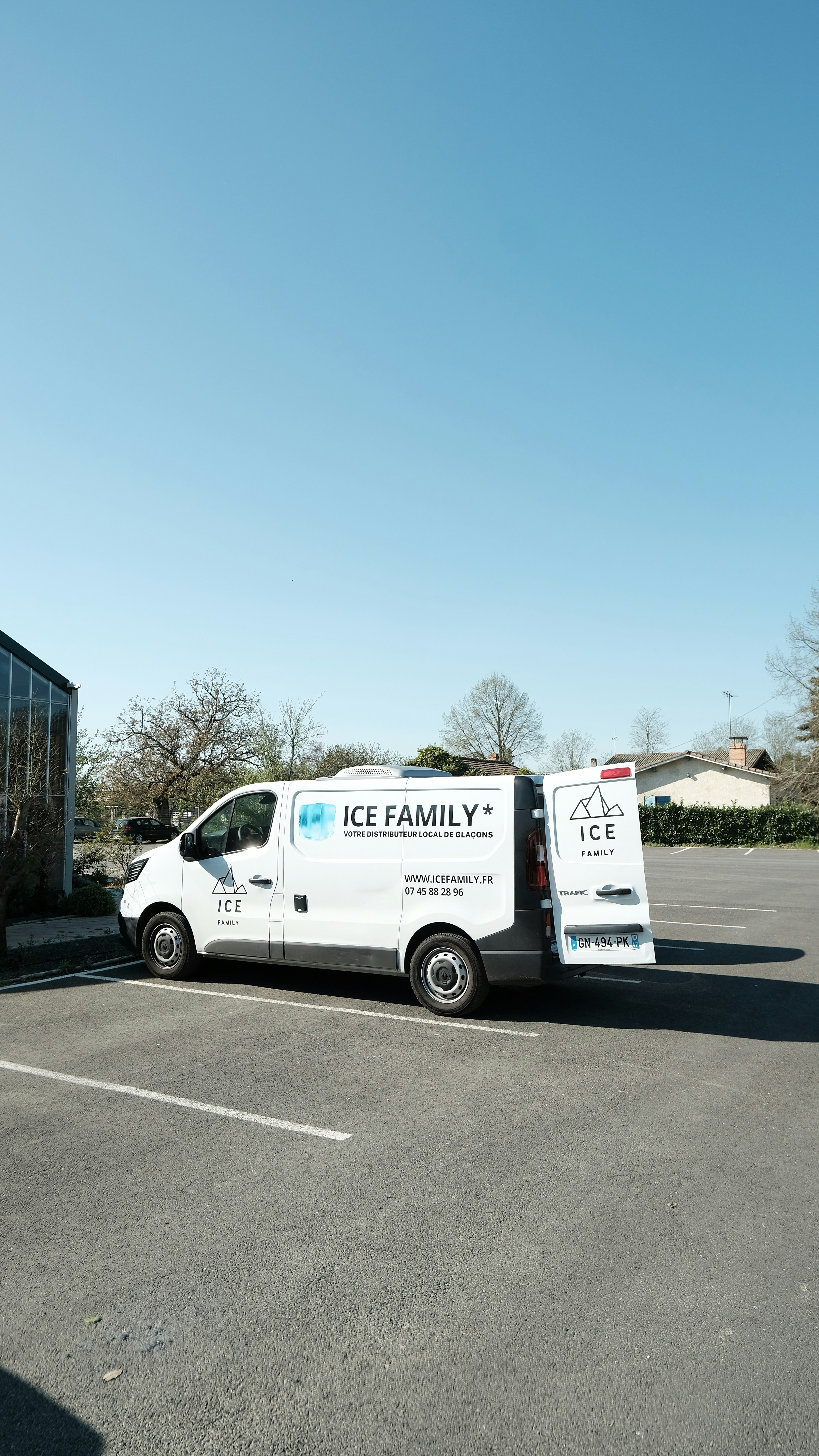 An "ice family" van parked outdoors on a sunny day.