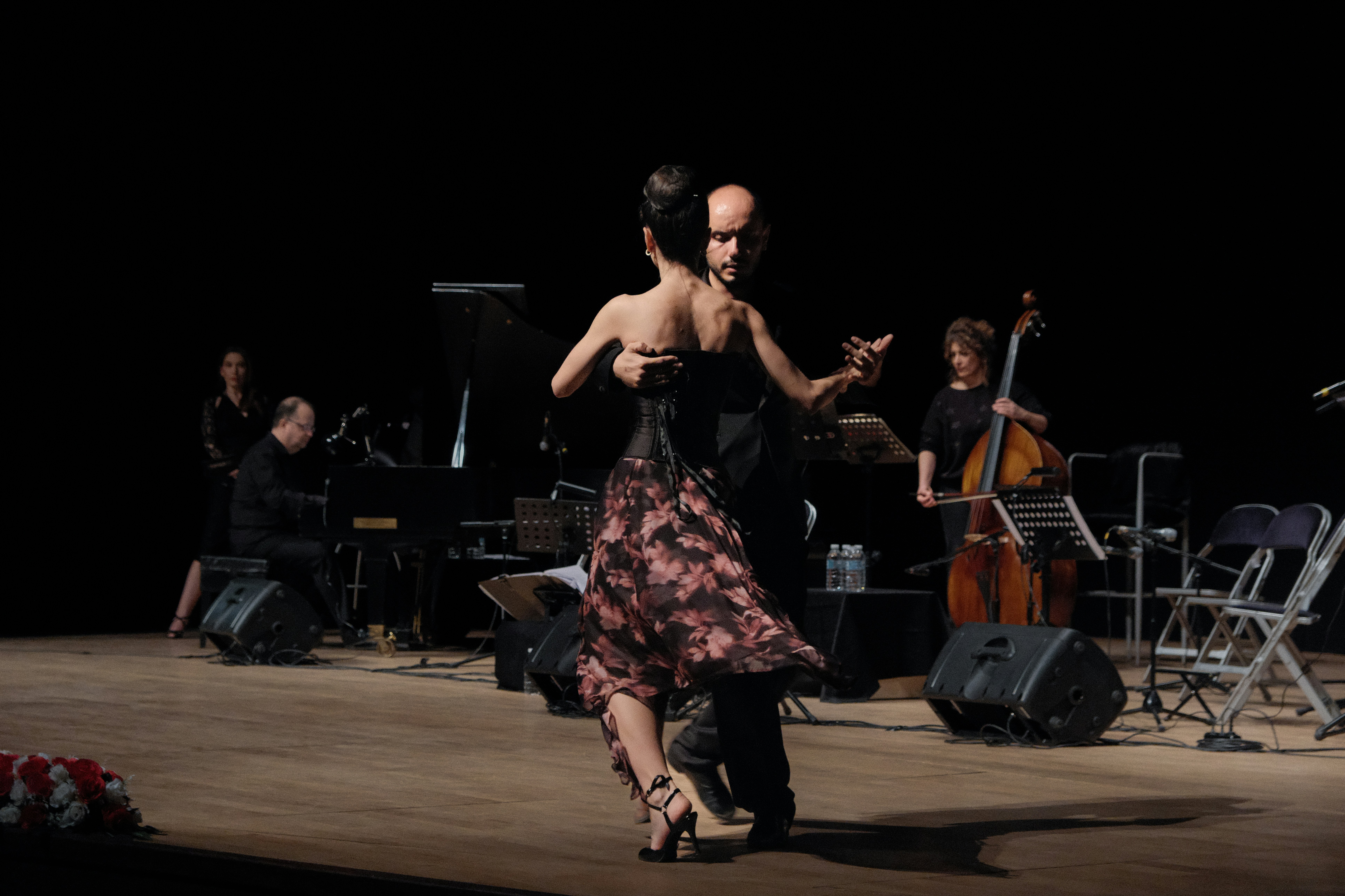 A couple dances tango with a live orchestra.