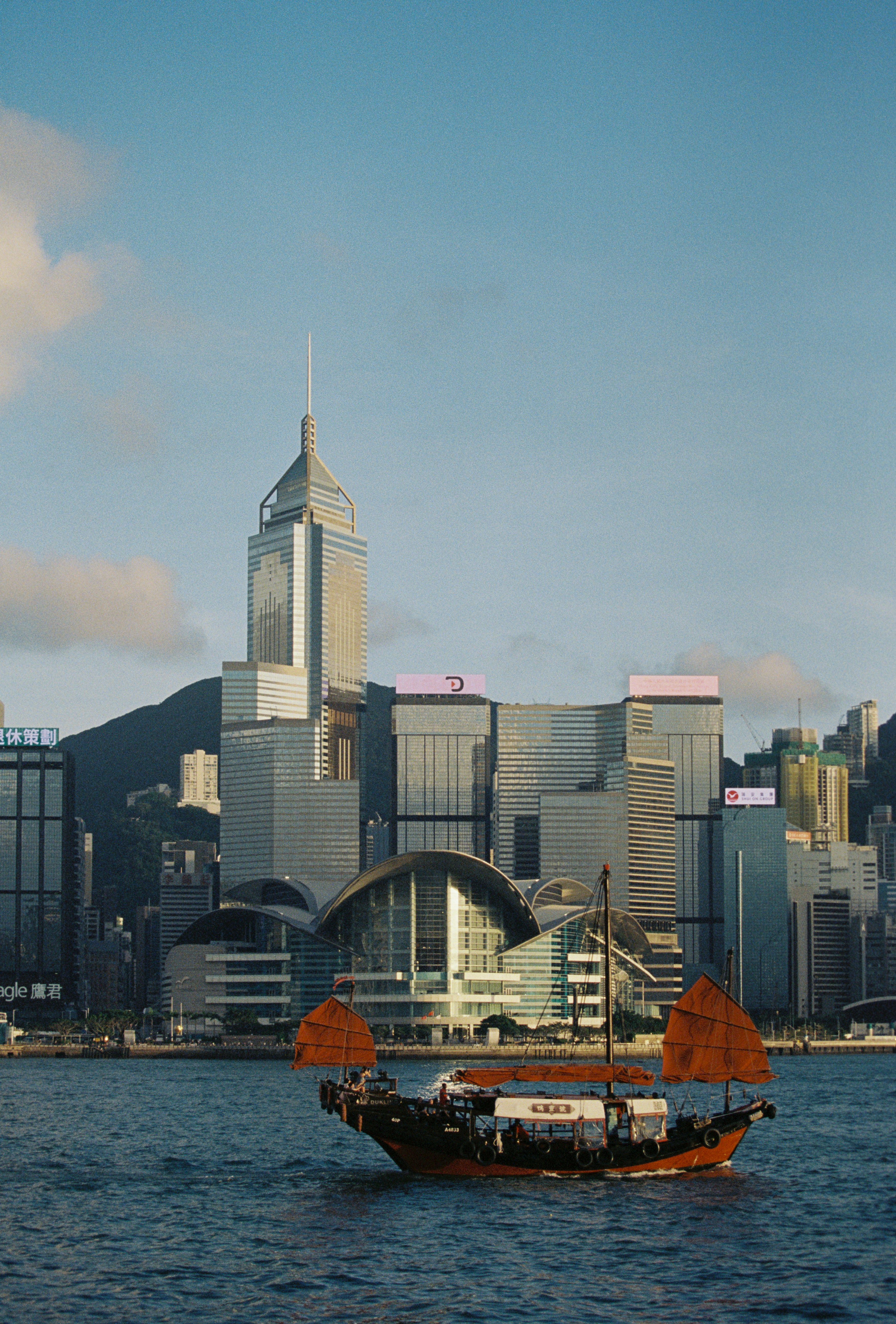A traditional boat sails near hong kong skyscrapers.