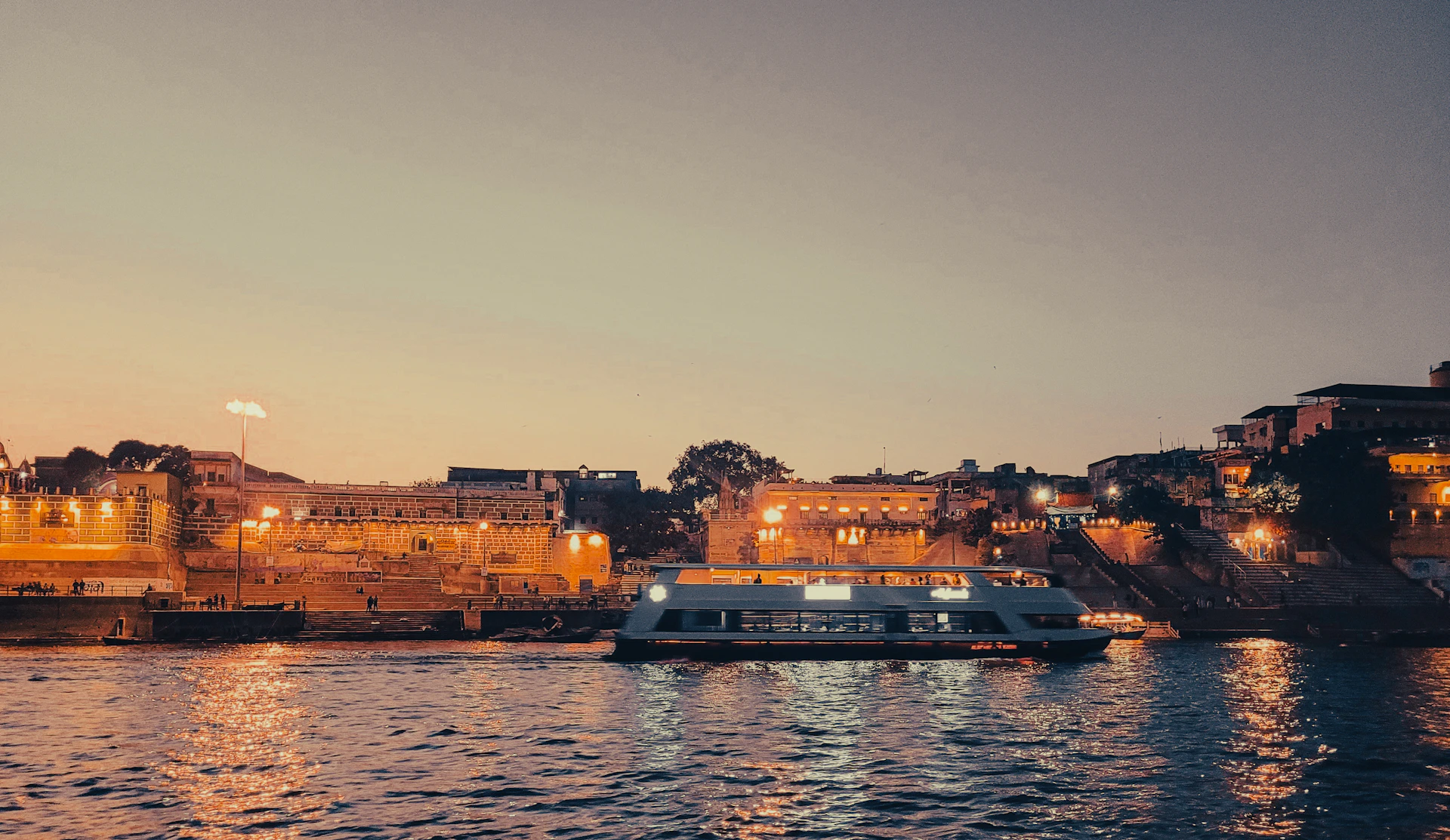 A boat sails on the river at dusk.