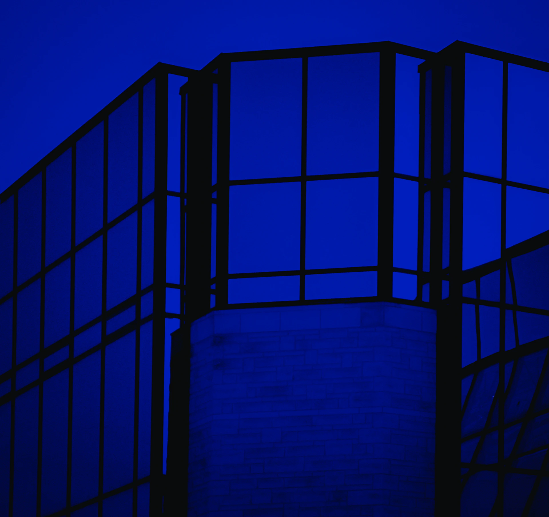 A modern building is bathed in deep blue light.