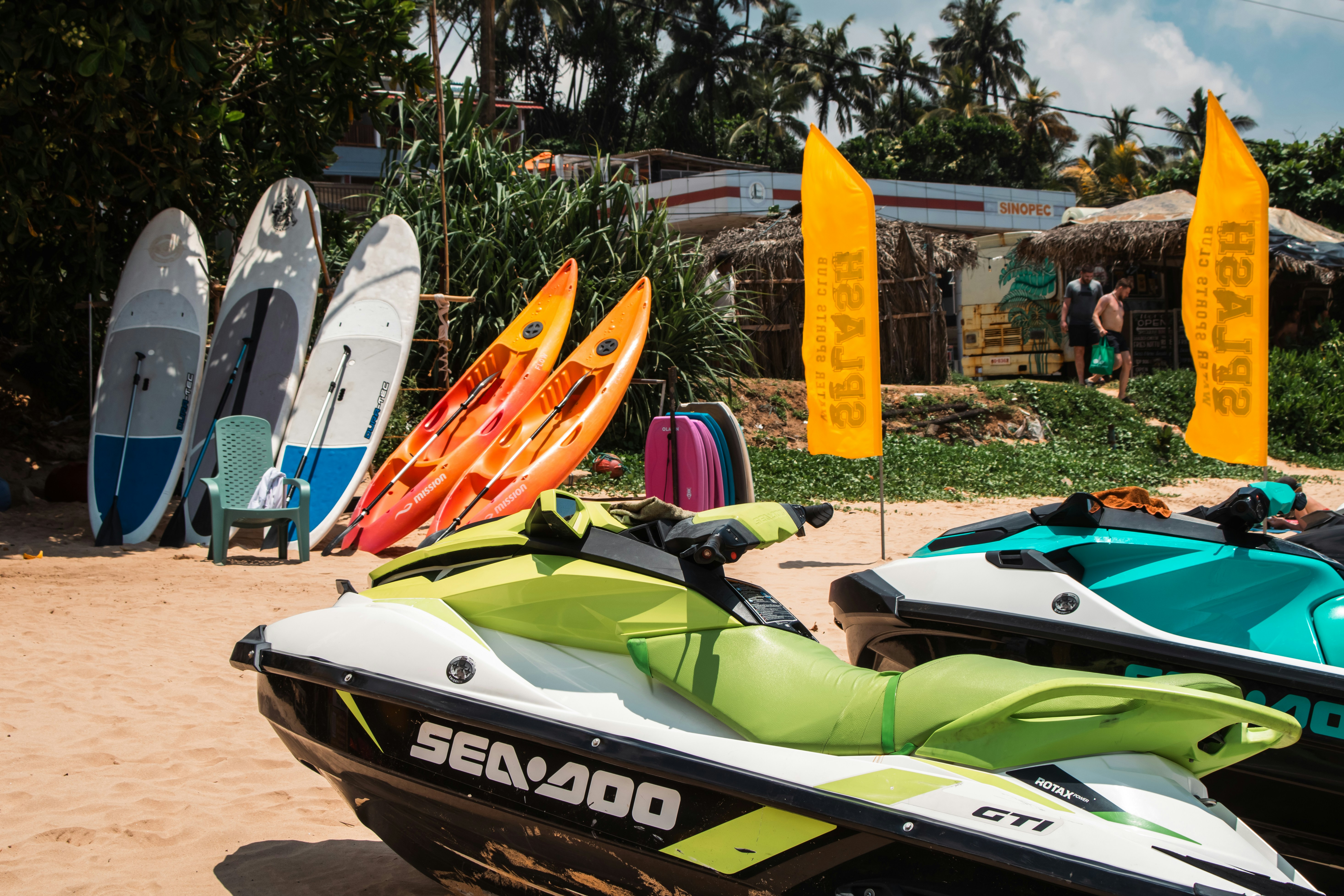 Beach scene with jet skis, kayaks, and surfboards.