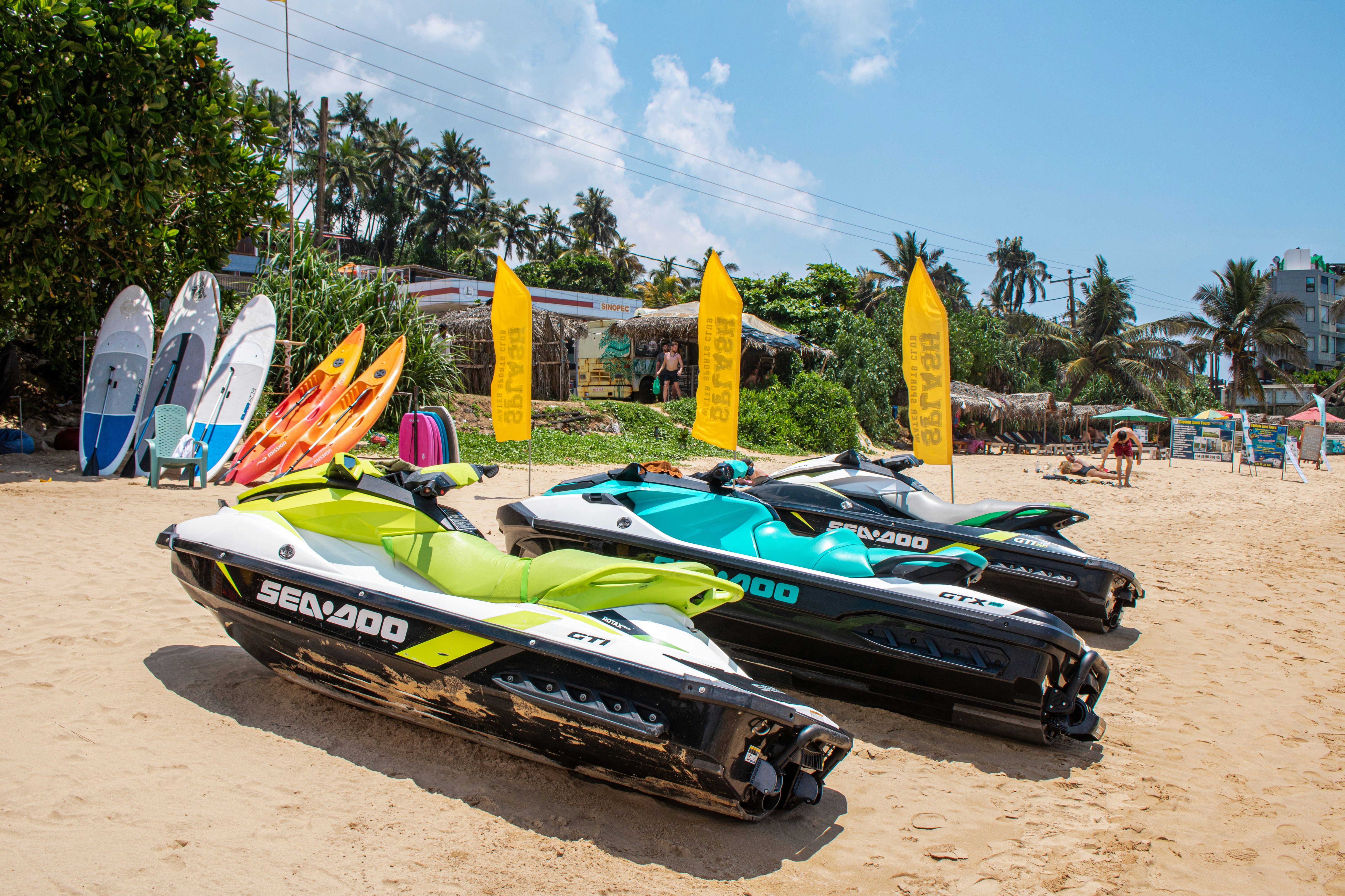 Jet skis and surfboards await on a sunny beach.