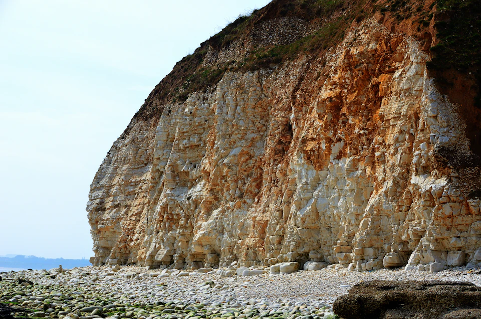 Rocky cliff face with white and orange hues, covered in small rocks and boulders