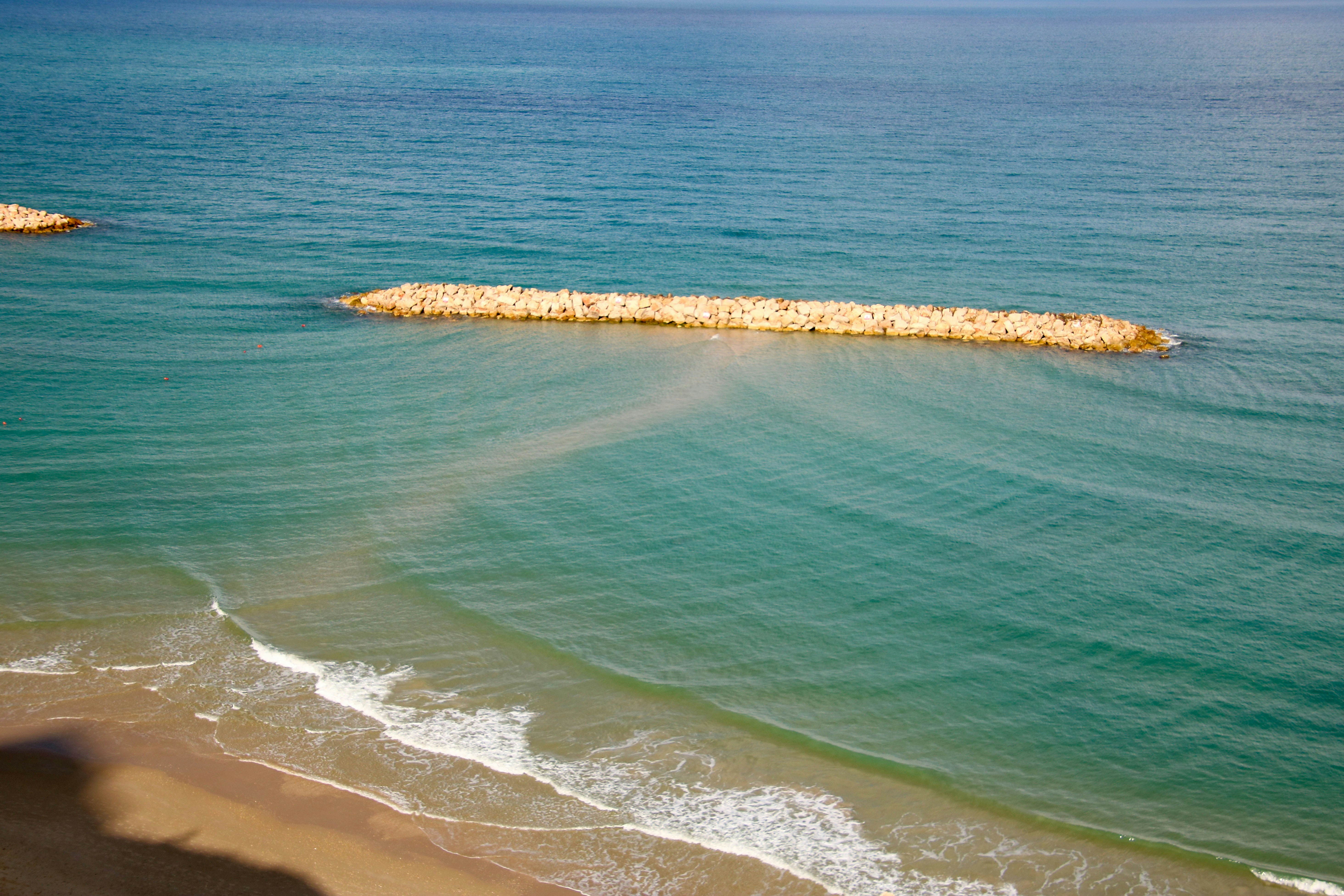 Calm turquoise water with a rock barrier.