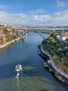 A boat sails underneath a grand bridge.