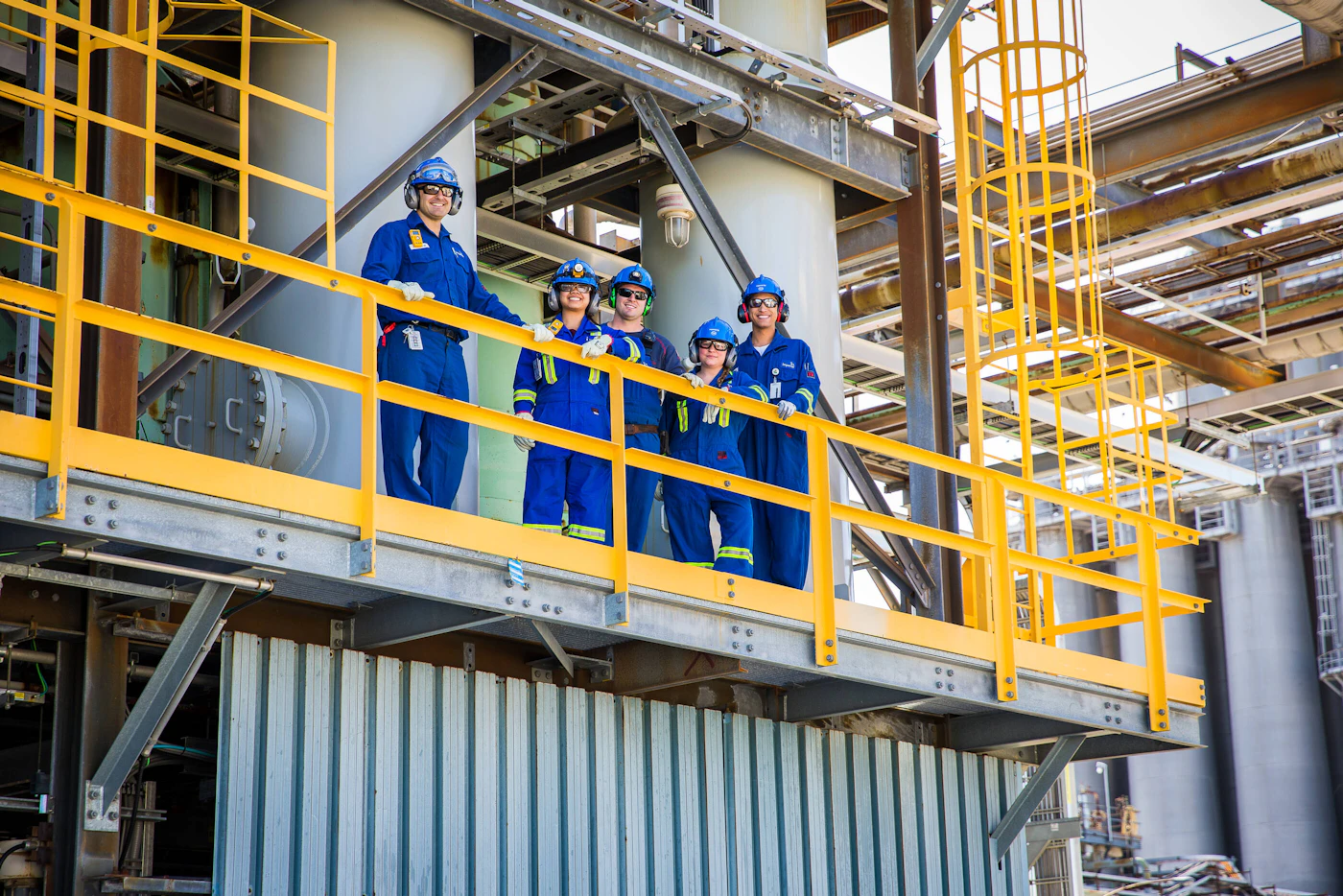 Industrial workers standing on a platform inside a manufacturing plant