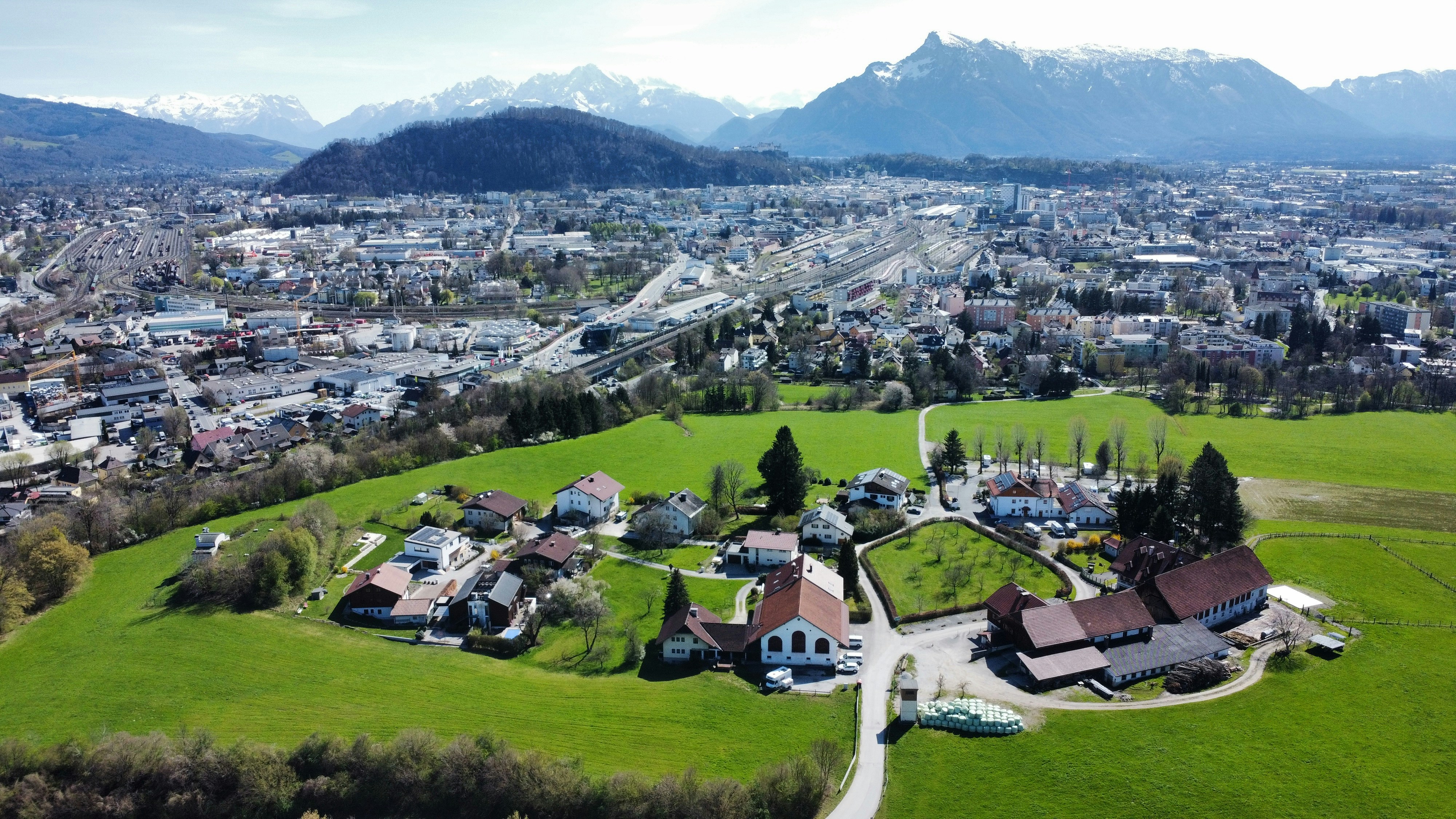 Green field and city meet snow-capped mountains.