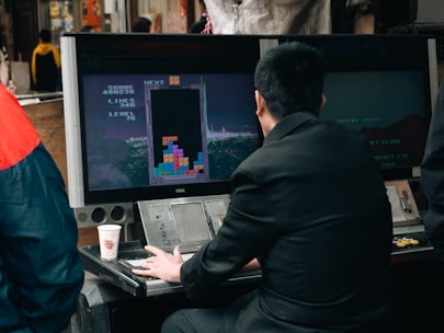 A man plays tetris on a vintage arcade game.