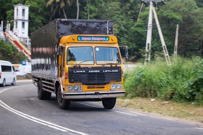A yellow truck drives on a road.