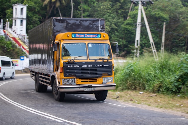 A yellow truck drives on a road.