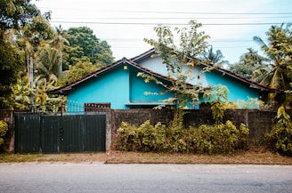 A blue house stands behind a green gate.