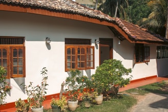 A white house has wooden windows and a red roof.