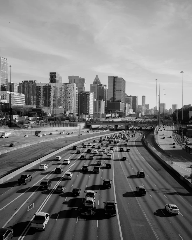 Cars travel on a highway towards a city skyline.