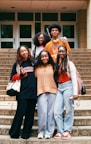 A group of smiling friends pose on some steps.