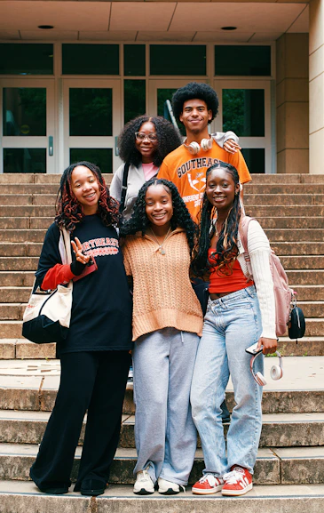 A group of smiling friends pose on some steps