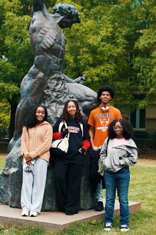 Four students pose for a photo near statue.