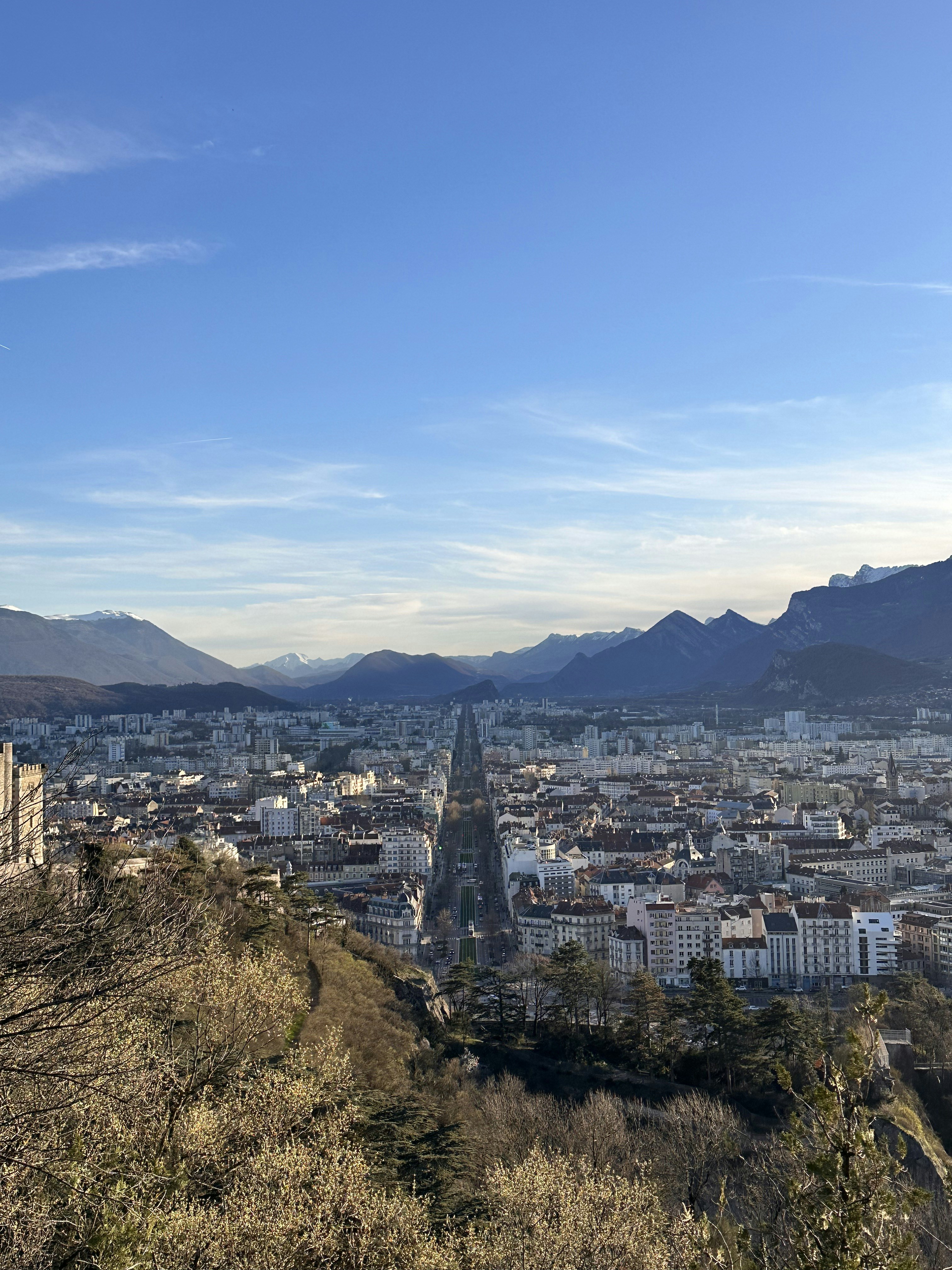 Cityscape under a vibrant blue sky with mountains.