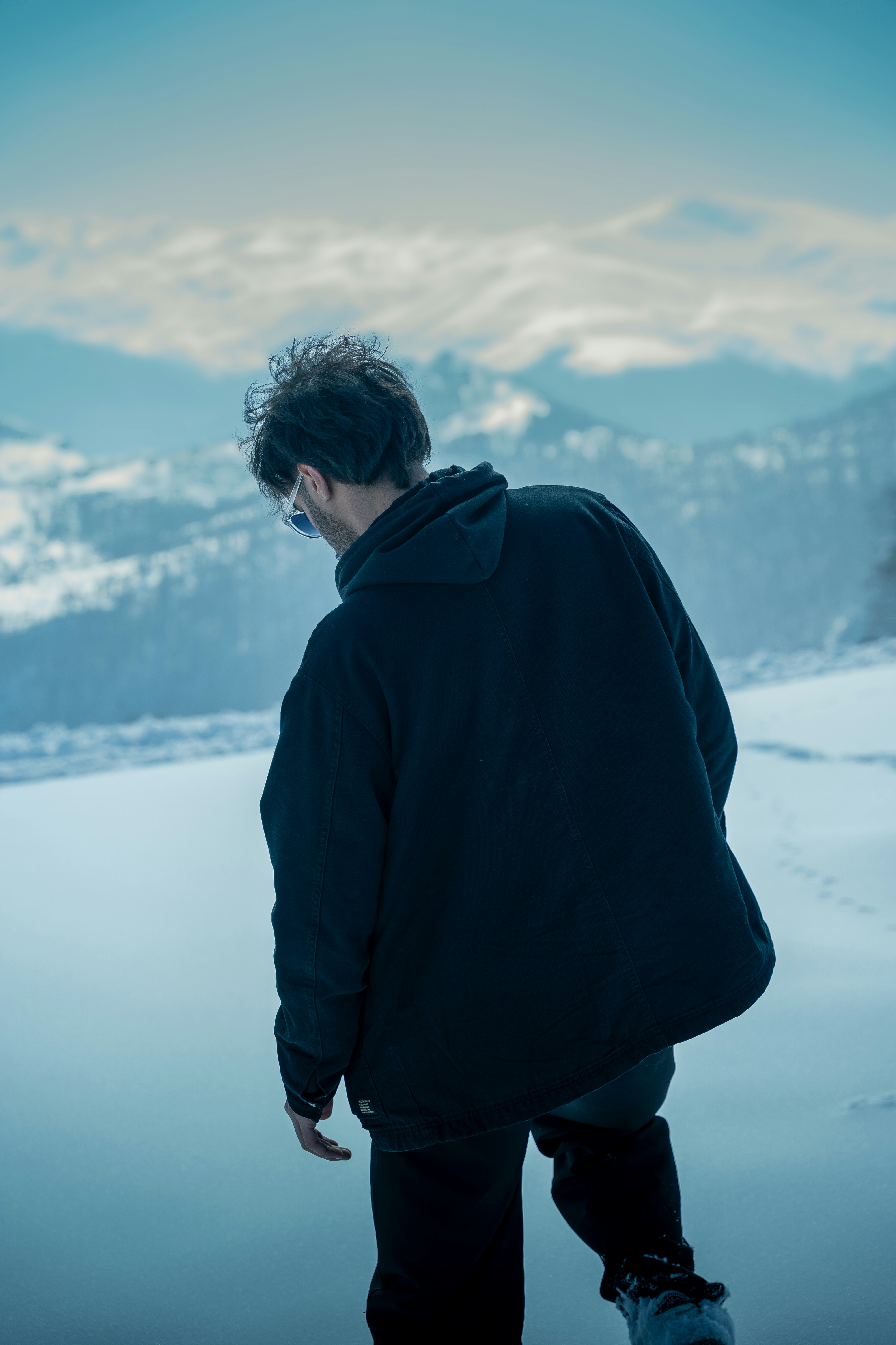 Man stands and gazes at a snowy mountain vista.