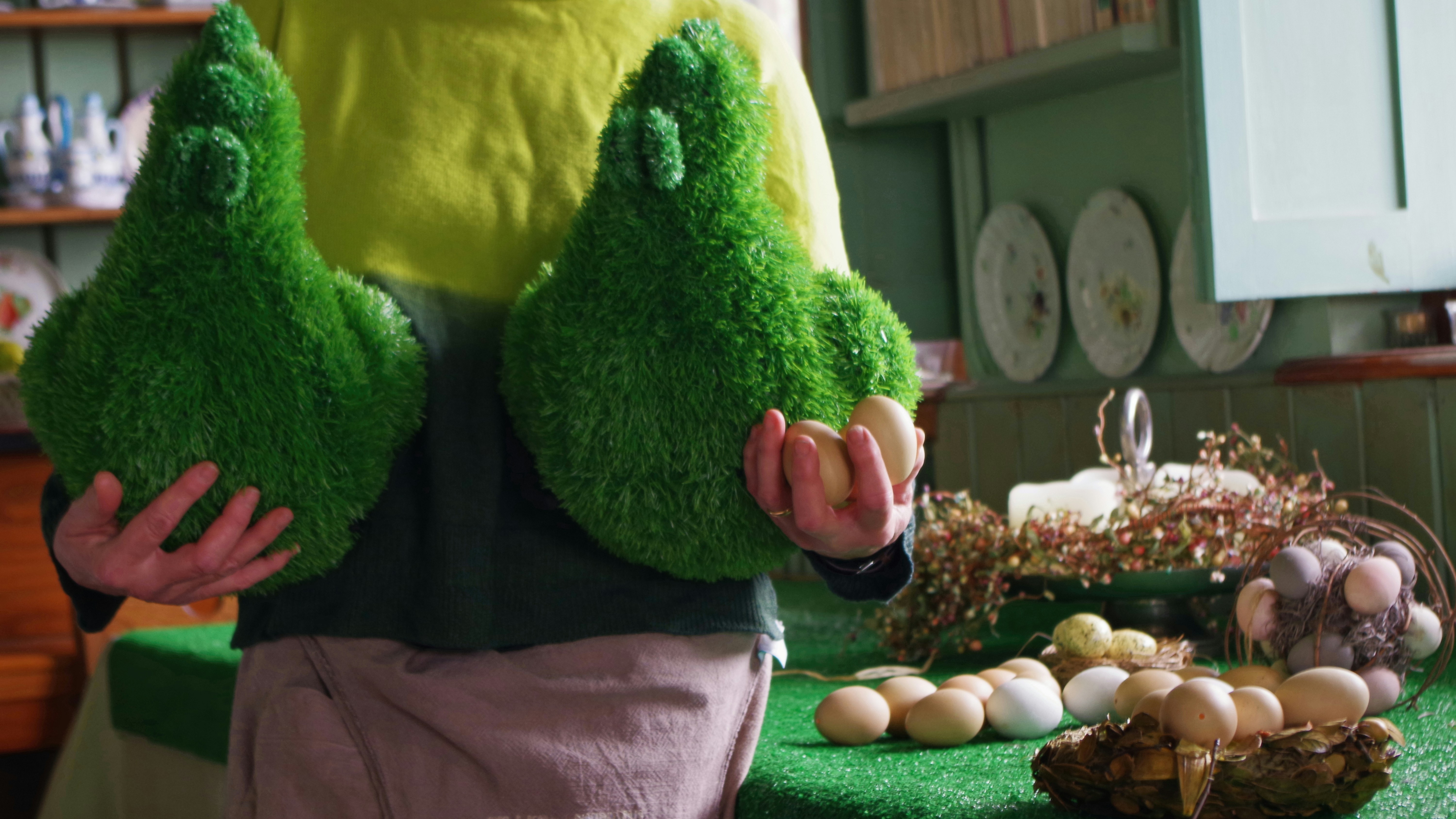 Someone is holding large, green, plant-covered objects.