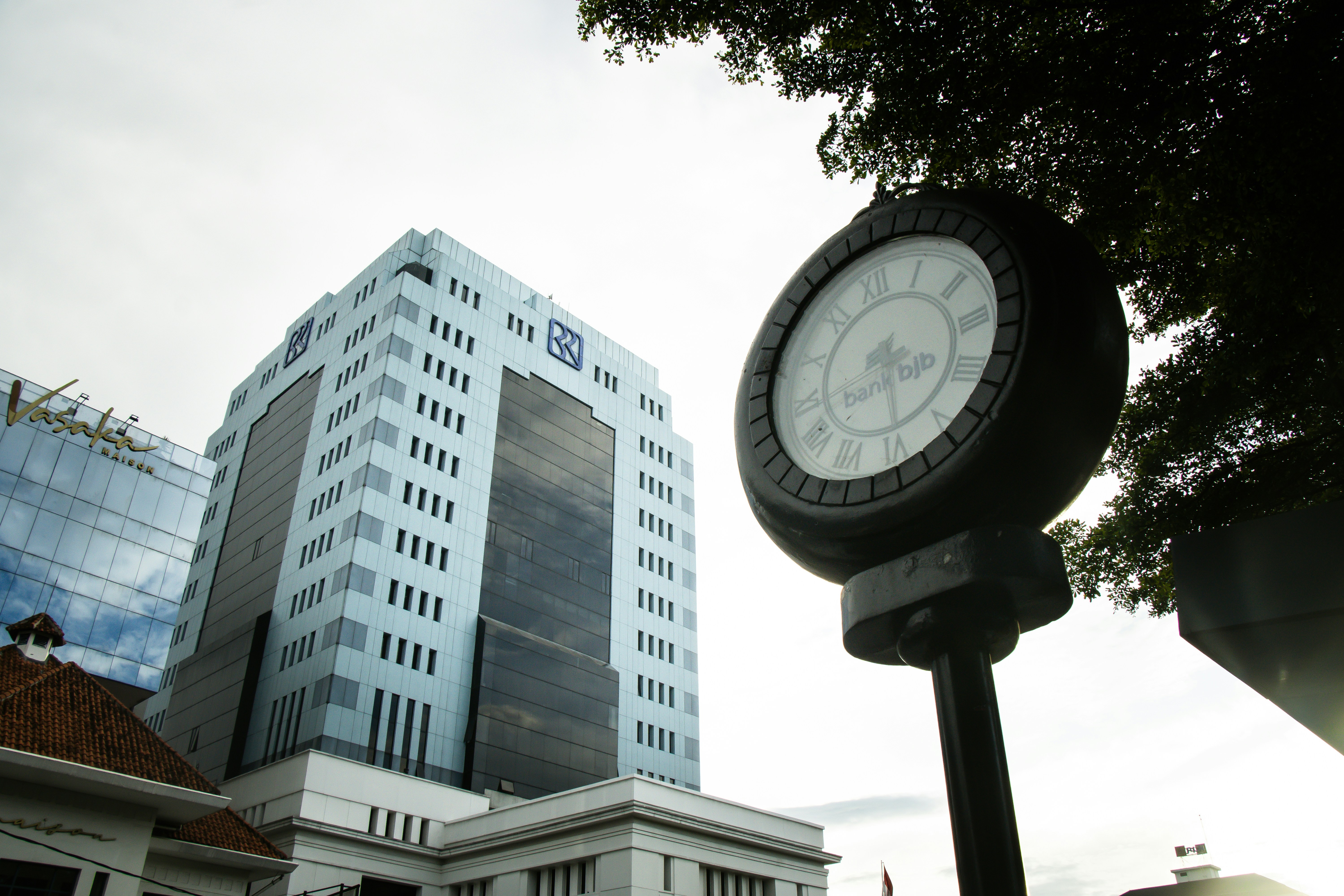 A clock sits in front of a large building.