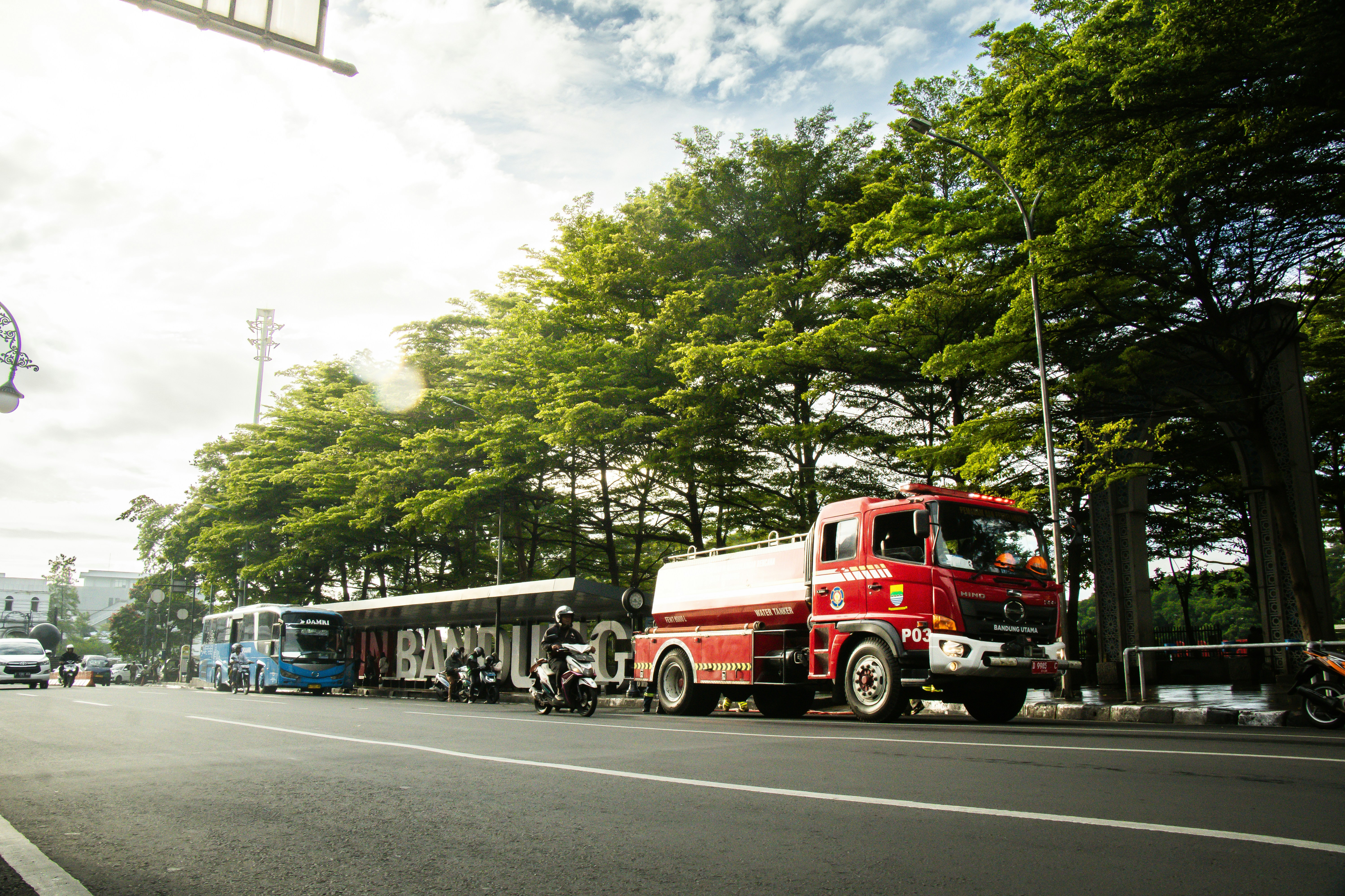 A red truck parks on a street by the trees.