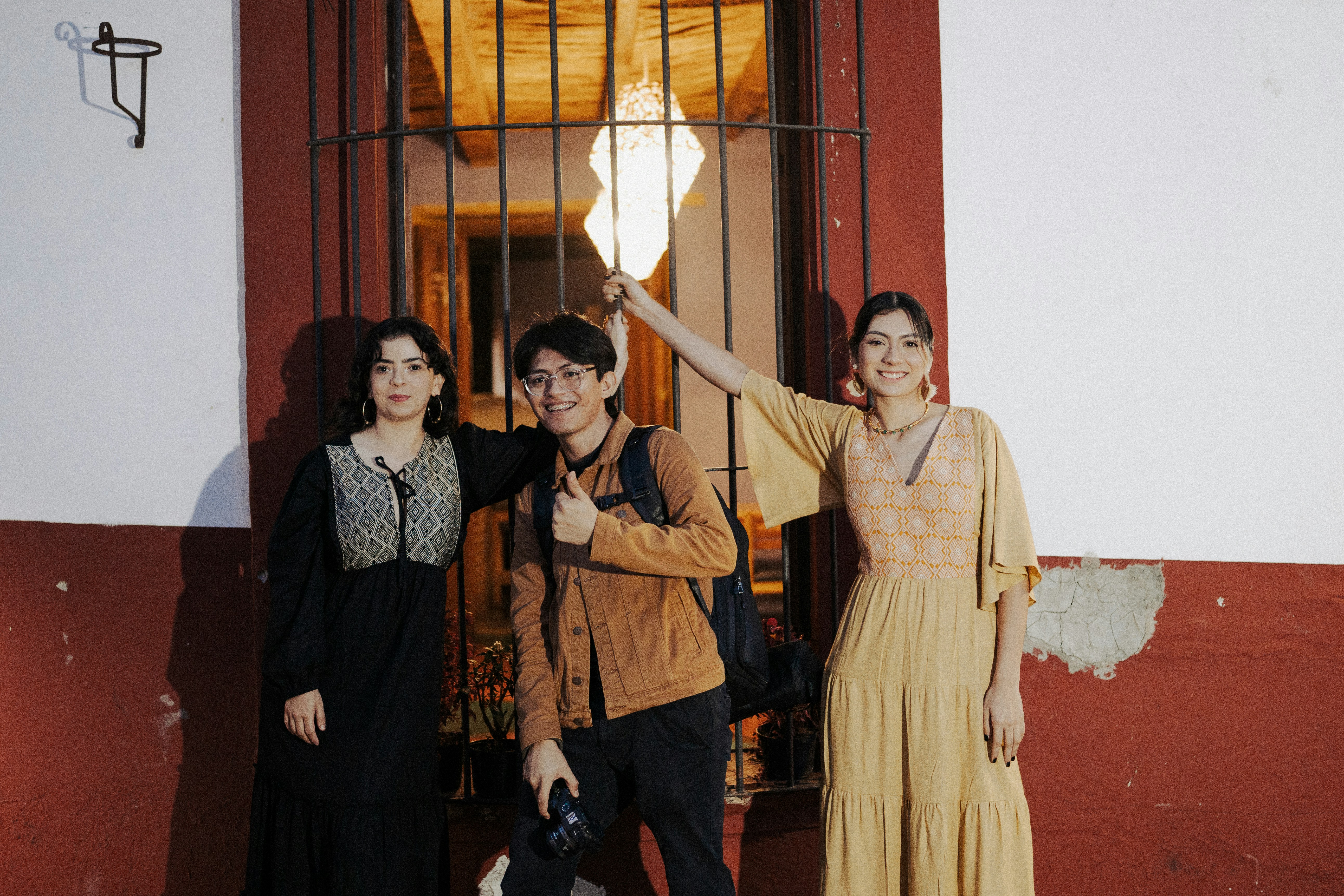 Three friends are posing near a window.